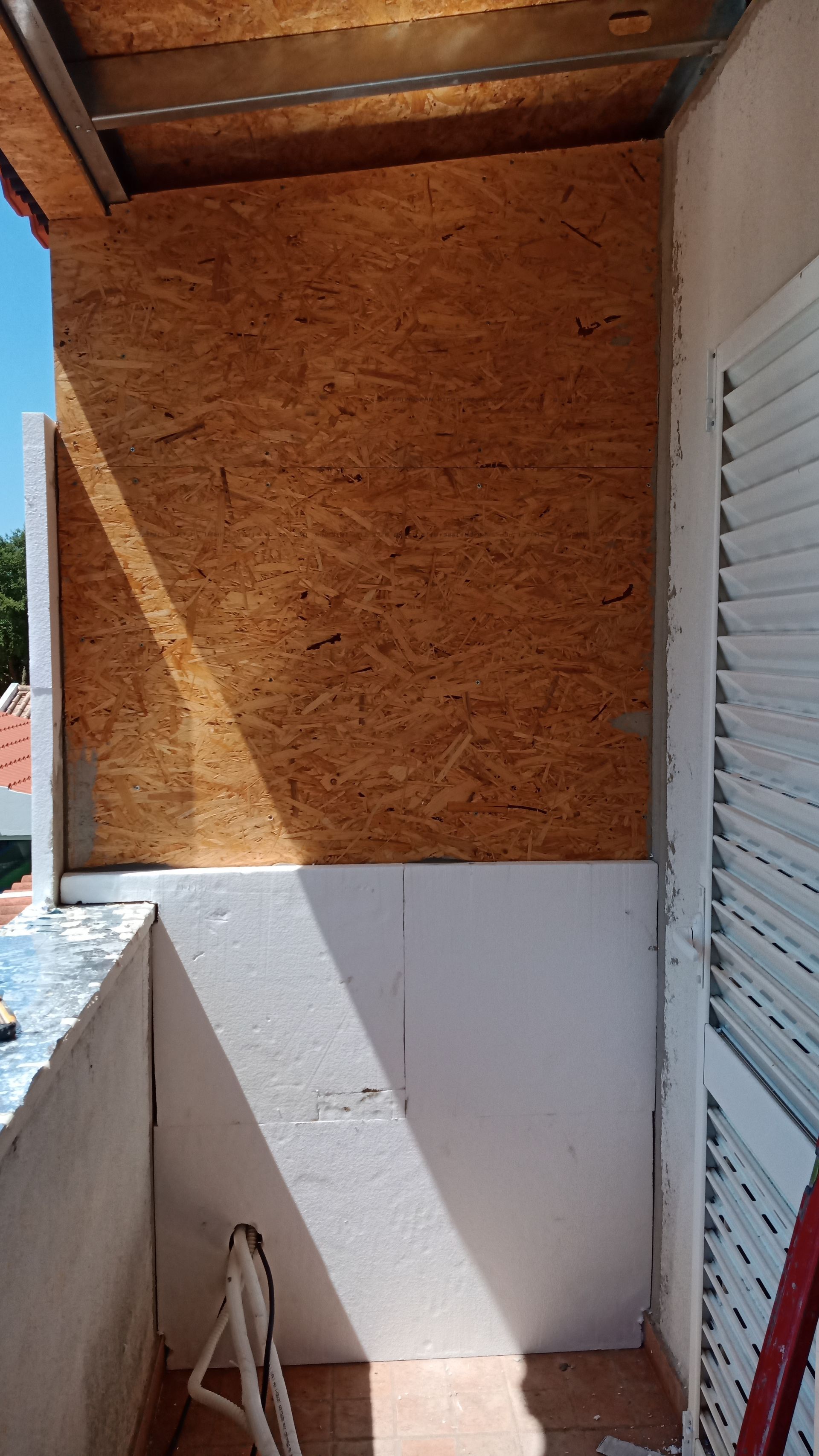 Varanda com madeira aparente e painéis isolantes brancos.