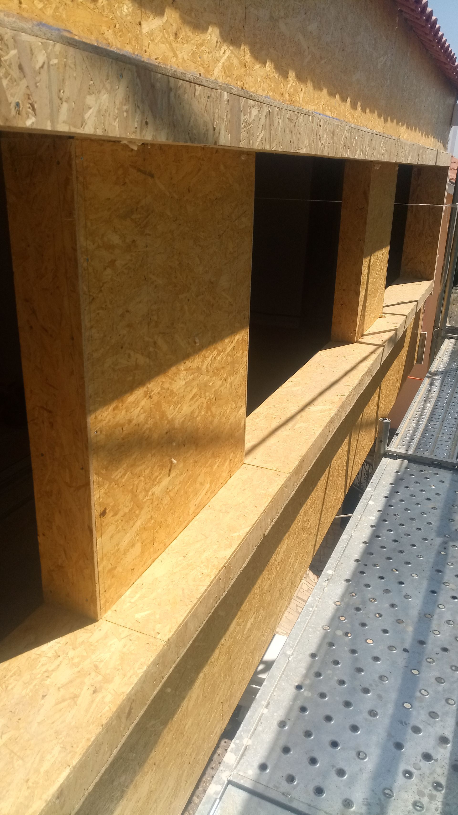 Canteiro de obras com estrutura de madeira para janelas. Luz solar.