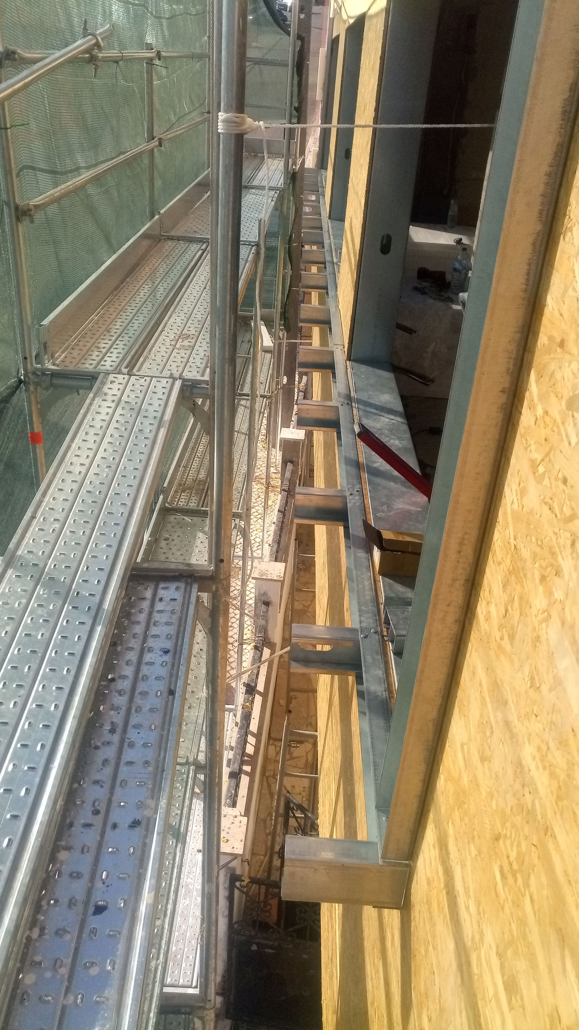 Andaimes montados ao lado de um edifício com painéis de madeira.