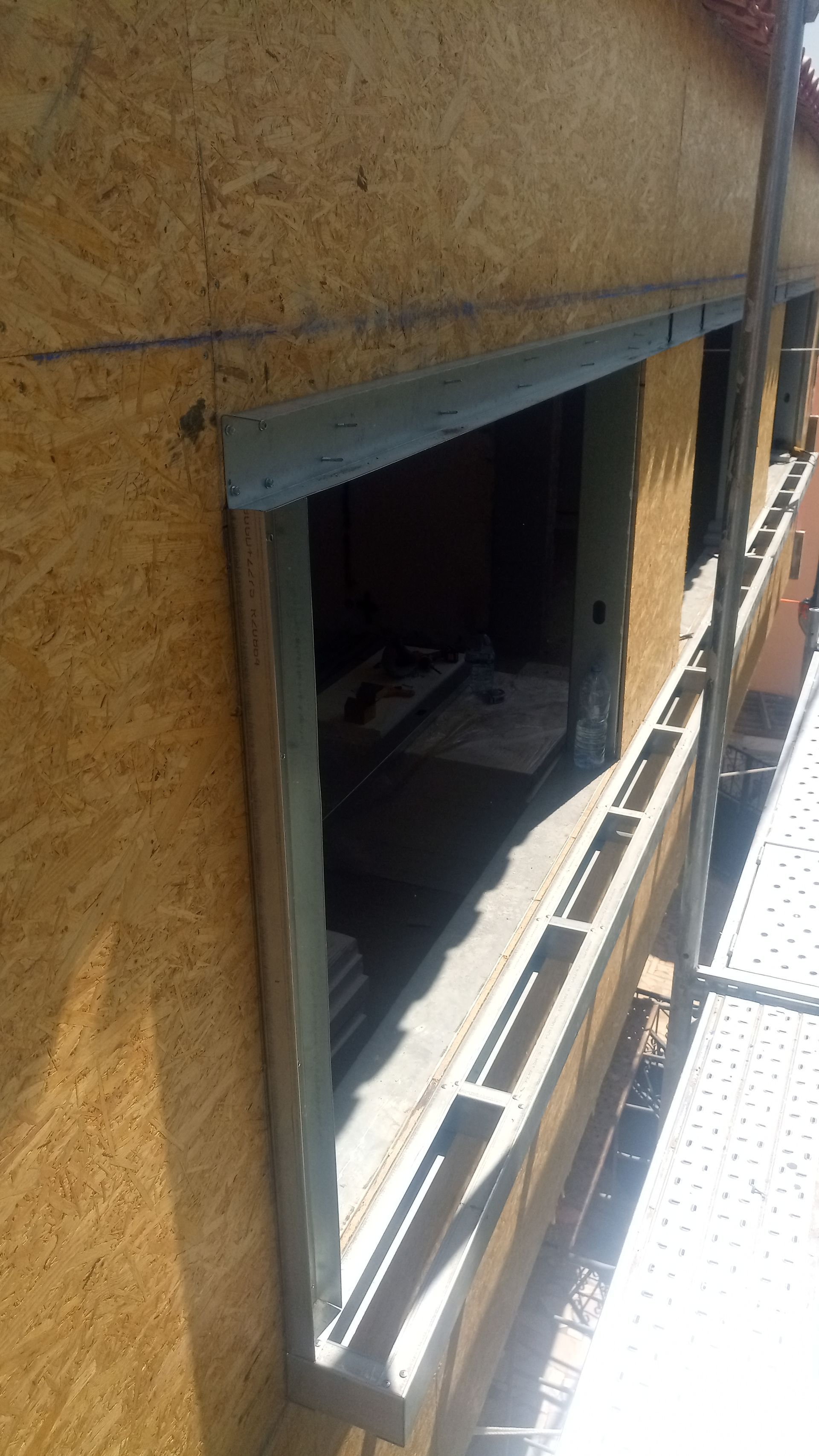 Parede externa com abertura para janela; revestimento em OSB visível, sem acabamento.