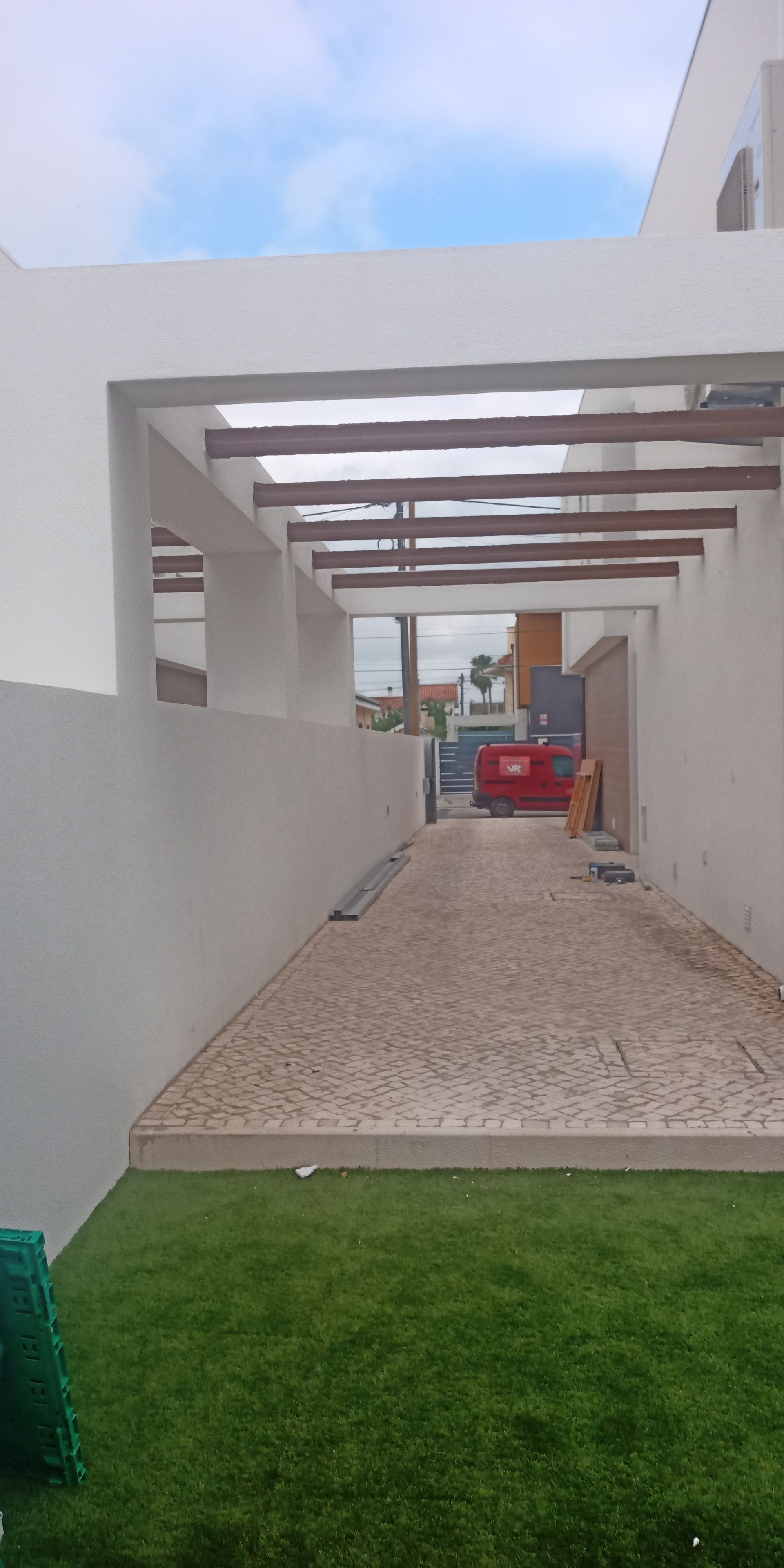 Uma entrada coberta com um caminho de pedra e grama verde à esquerda, que leva a uma casa.