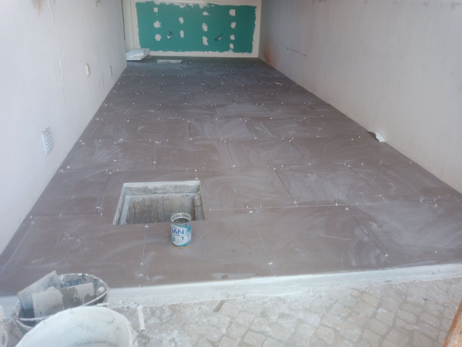 Quarto interior em construção com piso de azulejo novo e uma abertura quadrada.