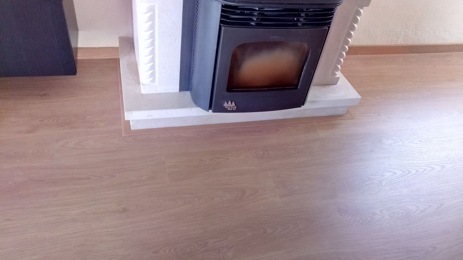 Fogão a pellets sobre uma plataforma branca, com piso castanho claro em contraste com o exterior.