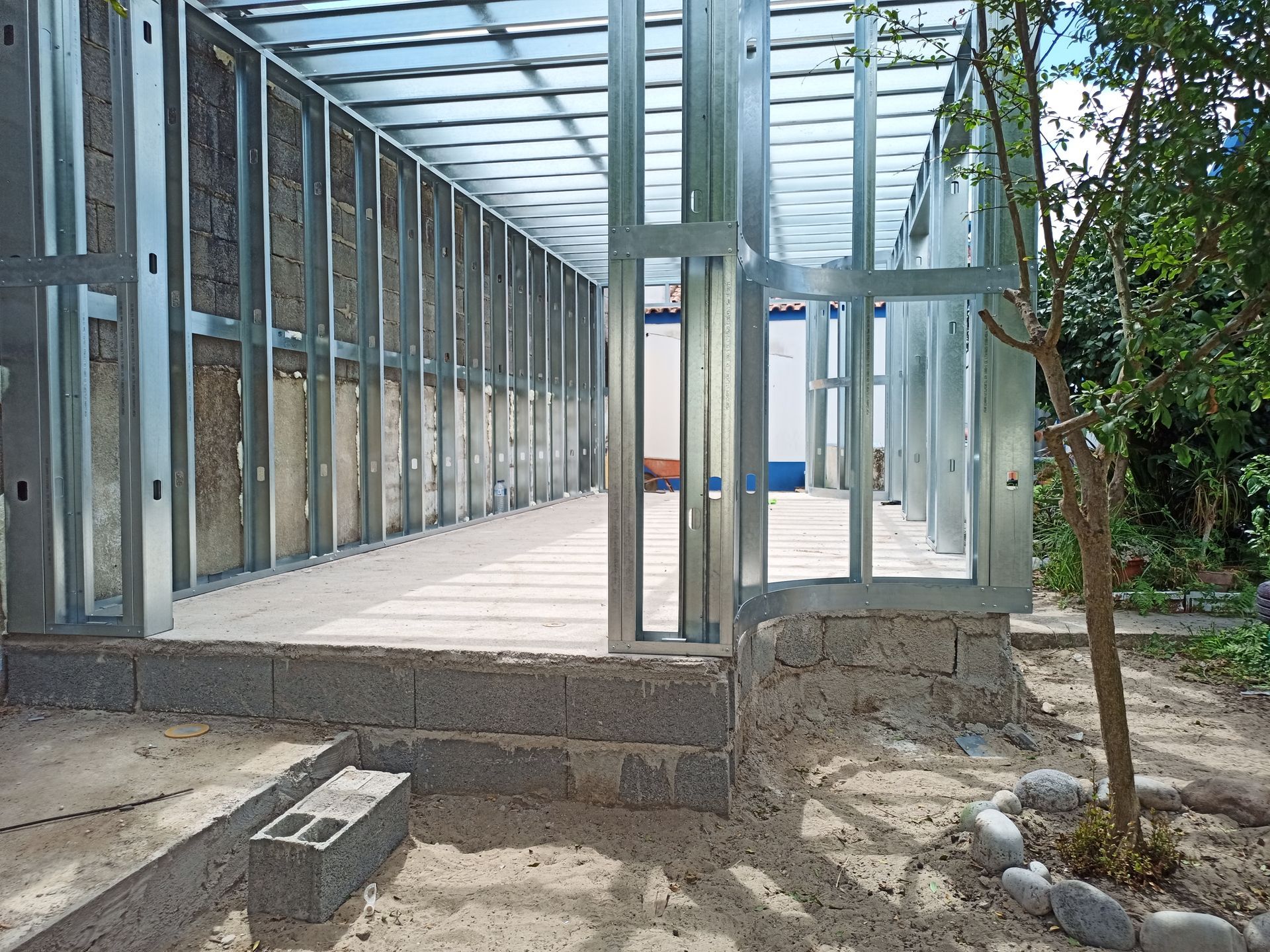 Estrutura metálica de um edifício em construção, sobre fundação de blocos, ao ar livre.
