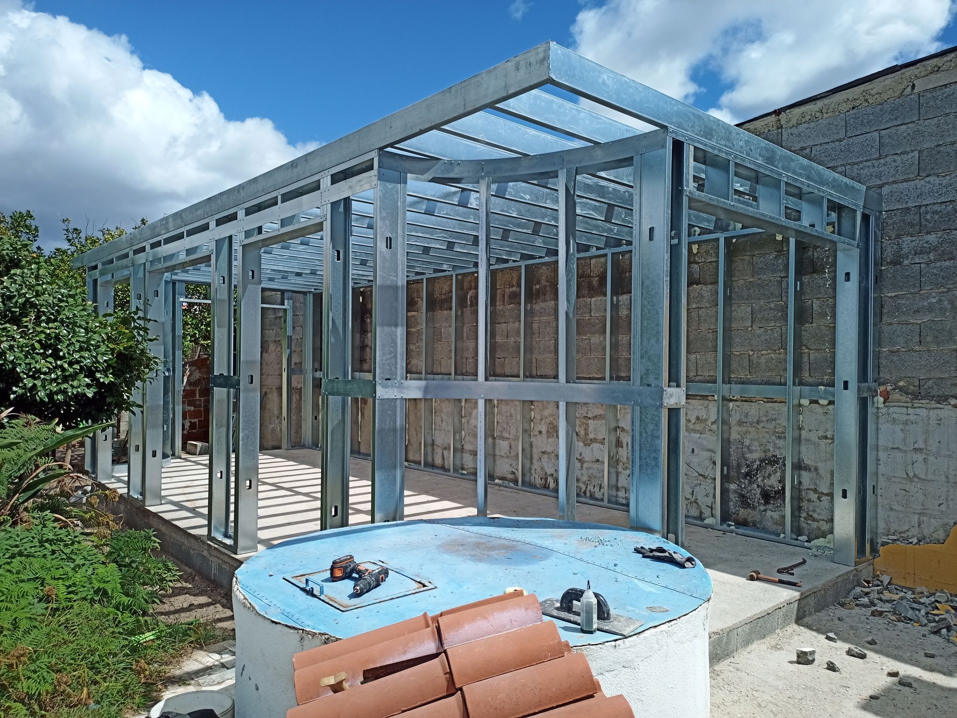 Estrutura metálica de um anexo em construção, contra um céu nublado.