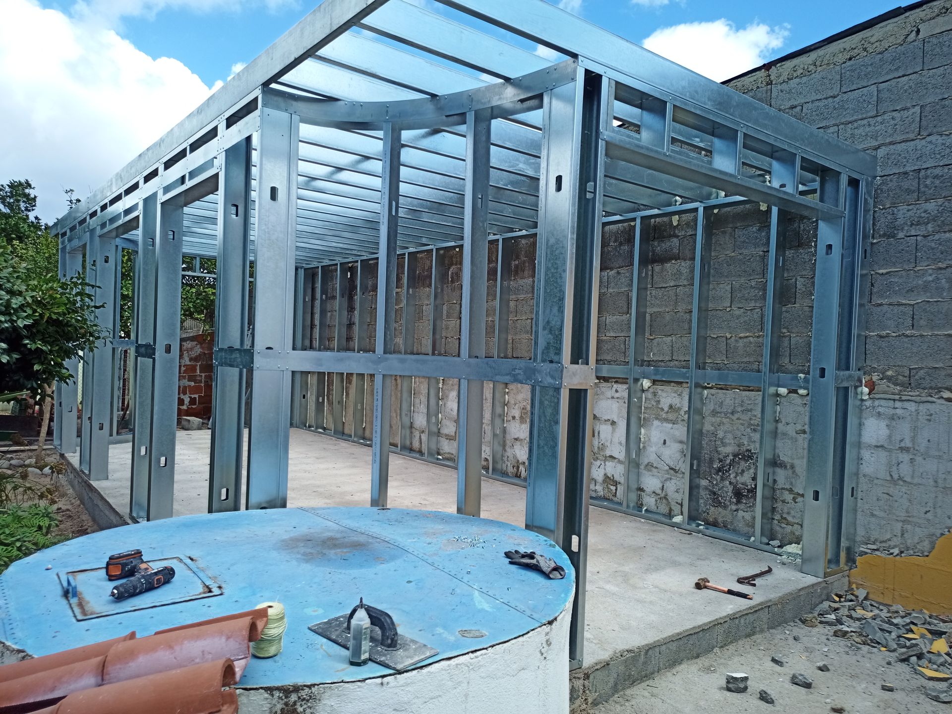 Estrutura metálica de um pequeno edifício em construção, com cobertura parcialmente translúcida.