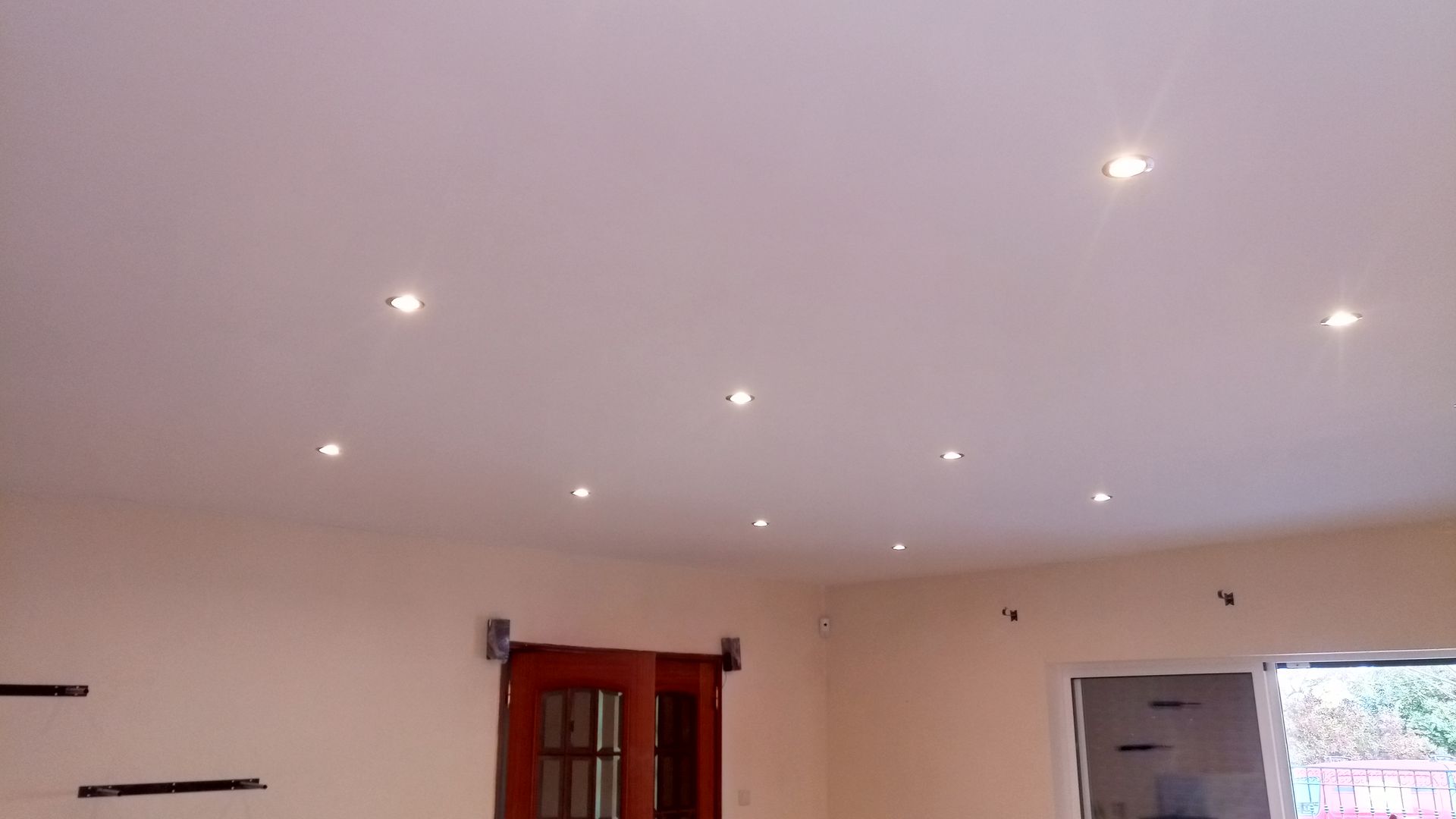 Teto branco com luzes embutidas, quarto com porta e janela.