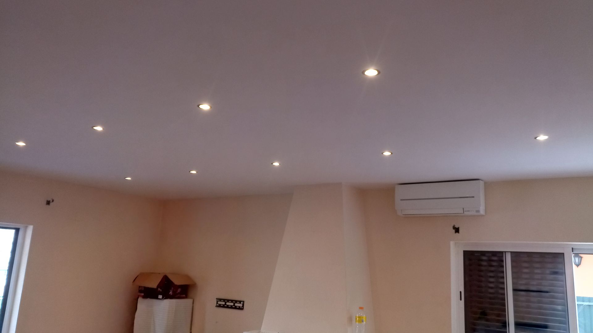 Quarto com teto bege, luzes embutidas, ar condicionado e janela.