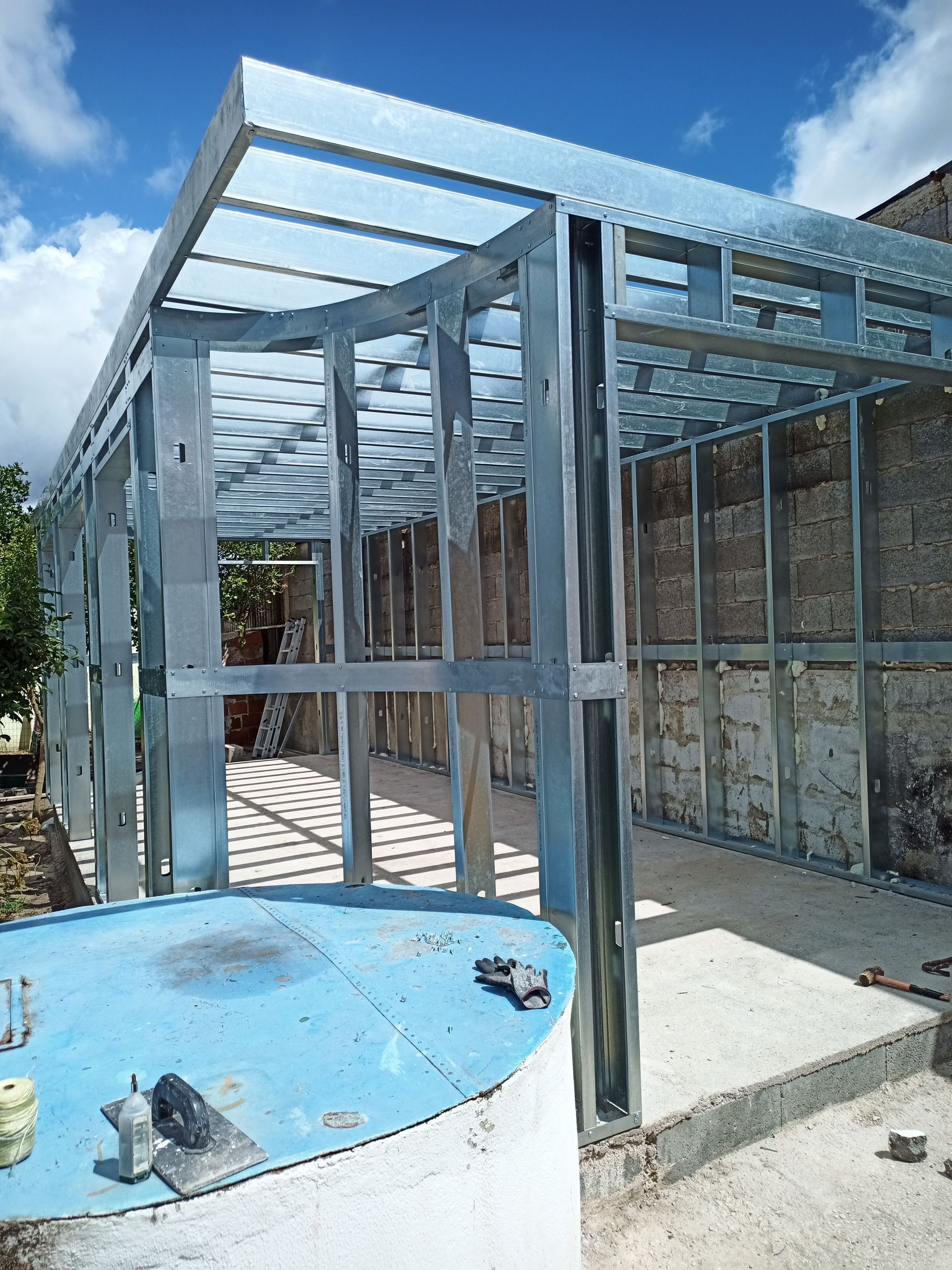 Estrutura metálica de um pequeno edifício sob um céu azul.