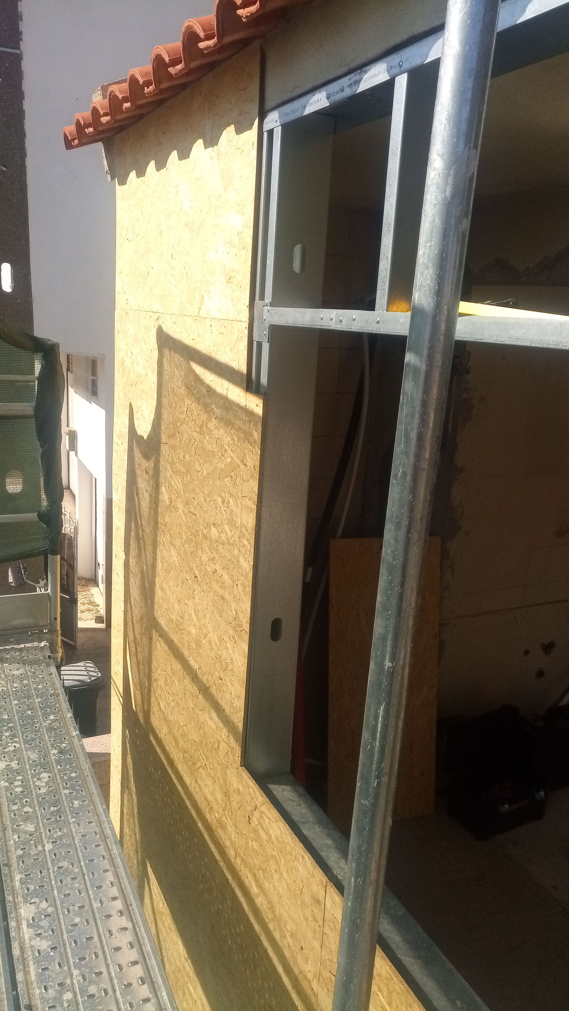 Parede externa com caixilho de janela, estuque e andaimes.