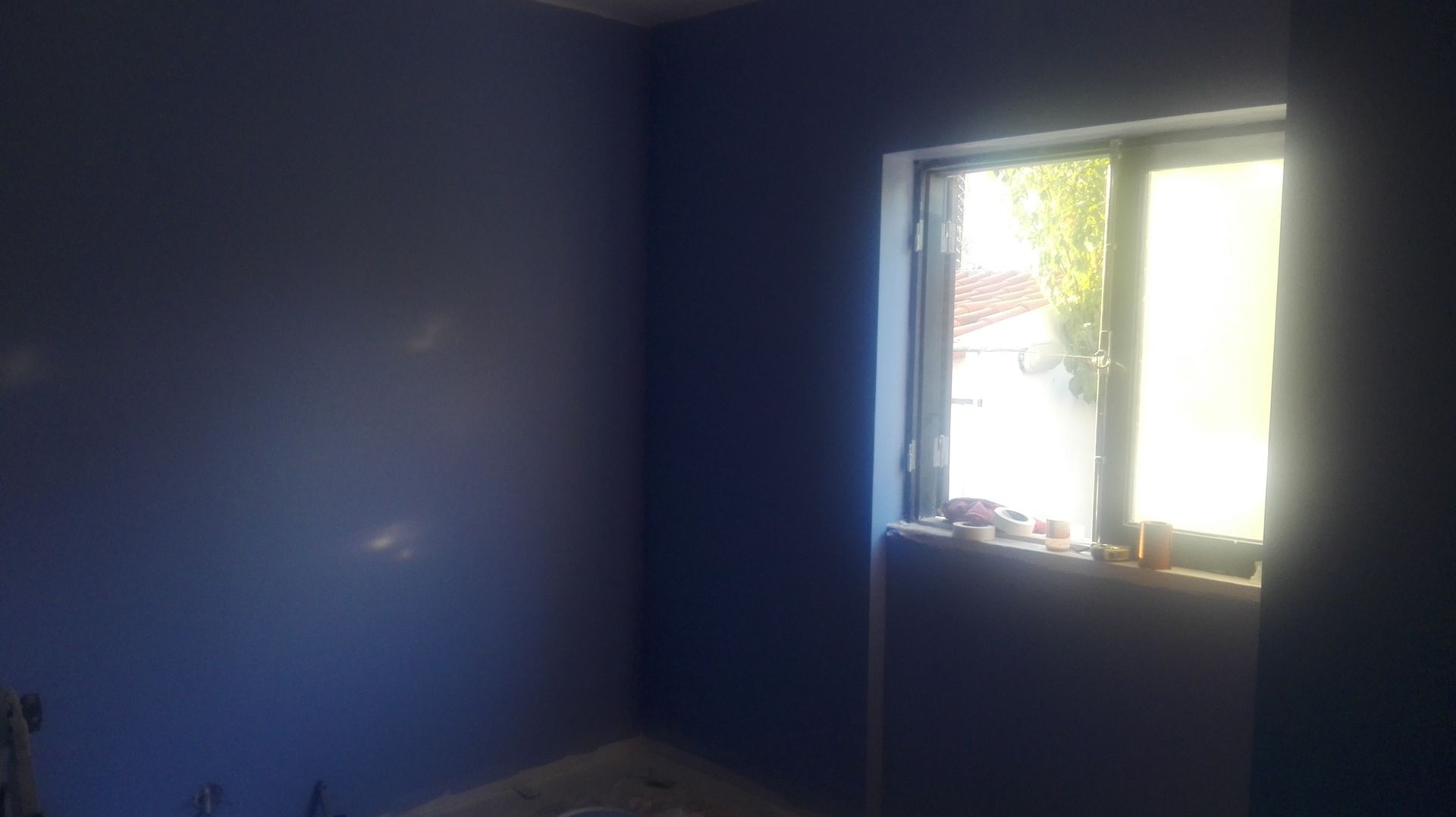 Quarto pintado de azul com uma janela que deixa entrar muita luz.