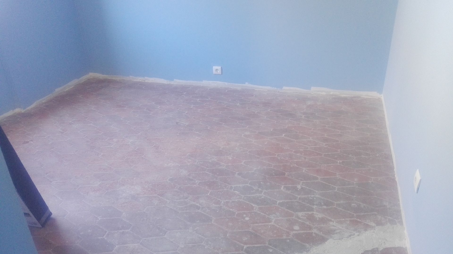 Quarto com piso nu e rachado e paredes azuis.