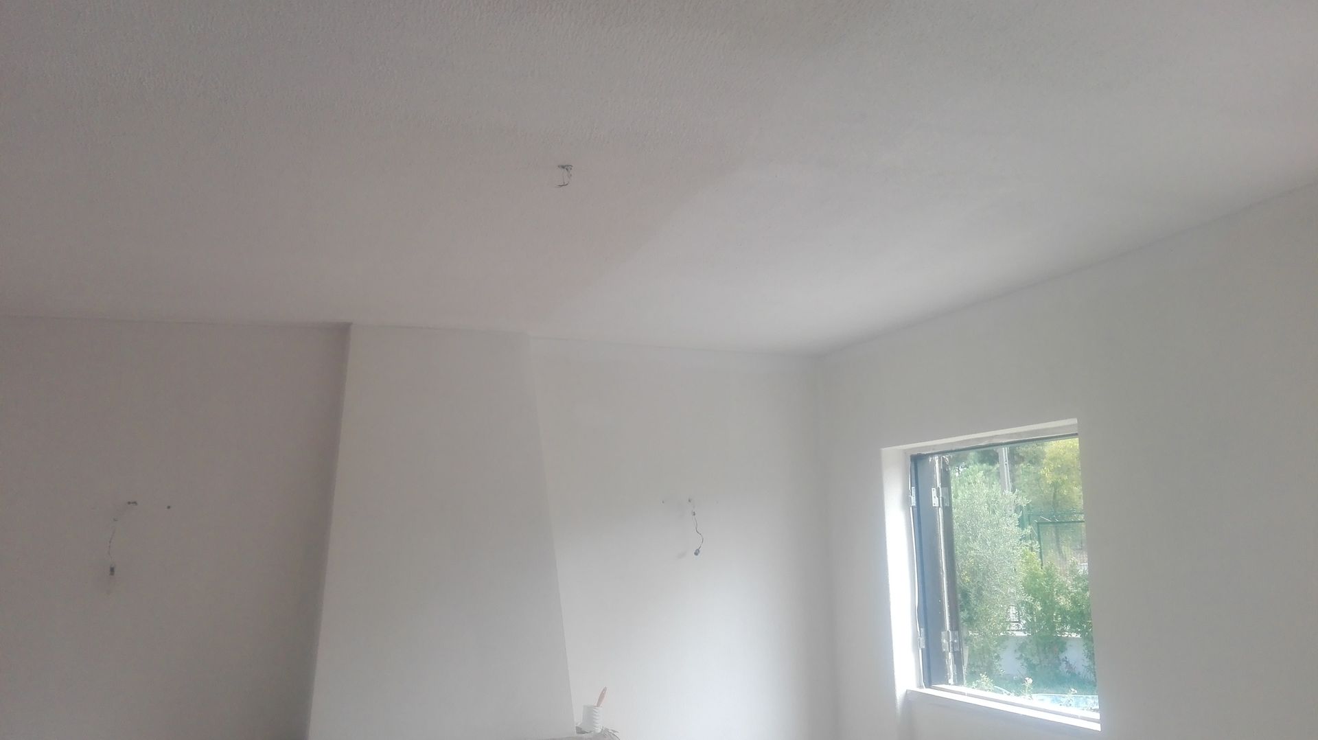 Quarto interior branco com janela e uma seção do teto.