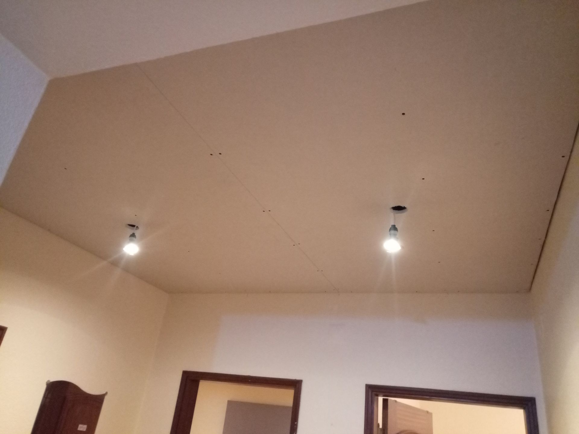 Quarto interior bege com duas lâmpadas acesas penduradas no teto.