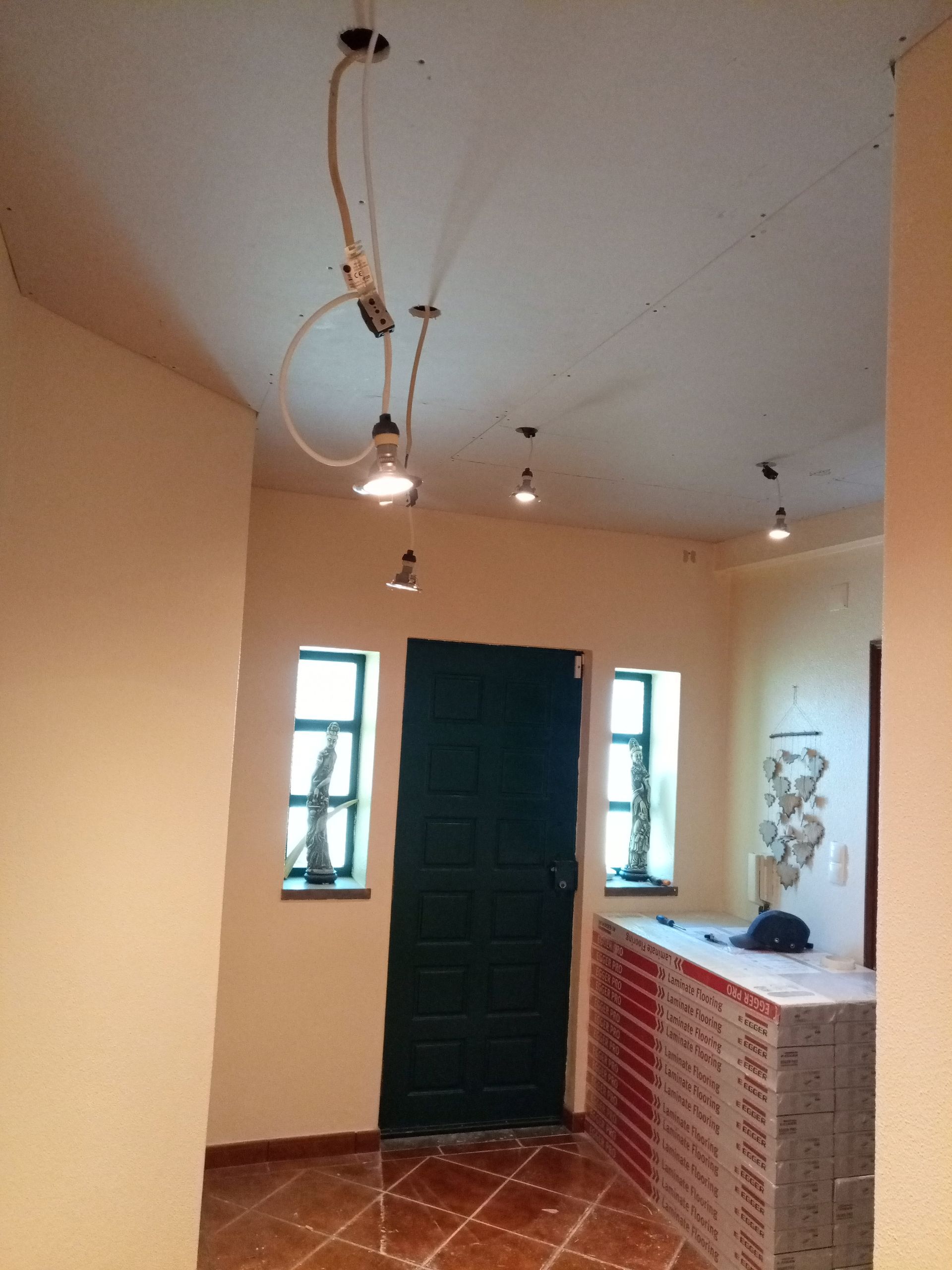 Corredor interno com luminárias pendentes, porta escura e janelas.