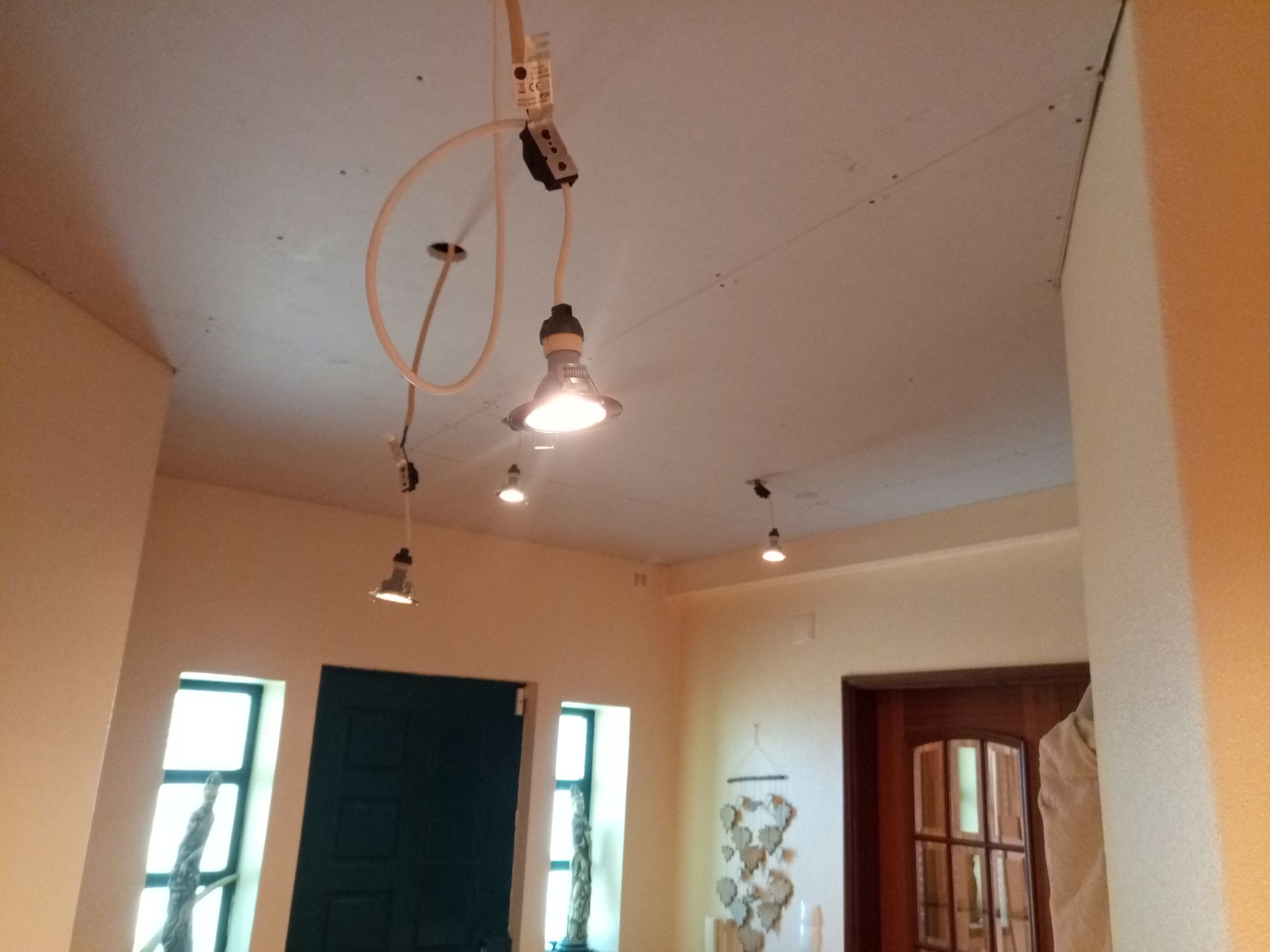 Interior com luzes de teto, paredes bege, janelas e uma porta verde-escura.