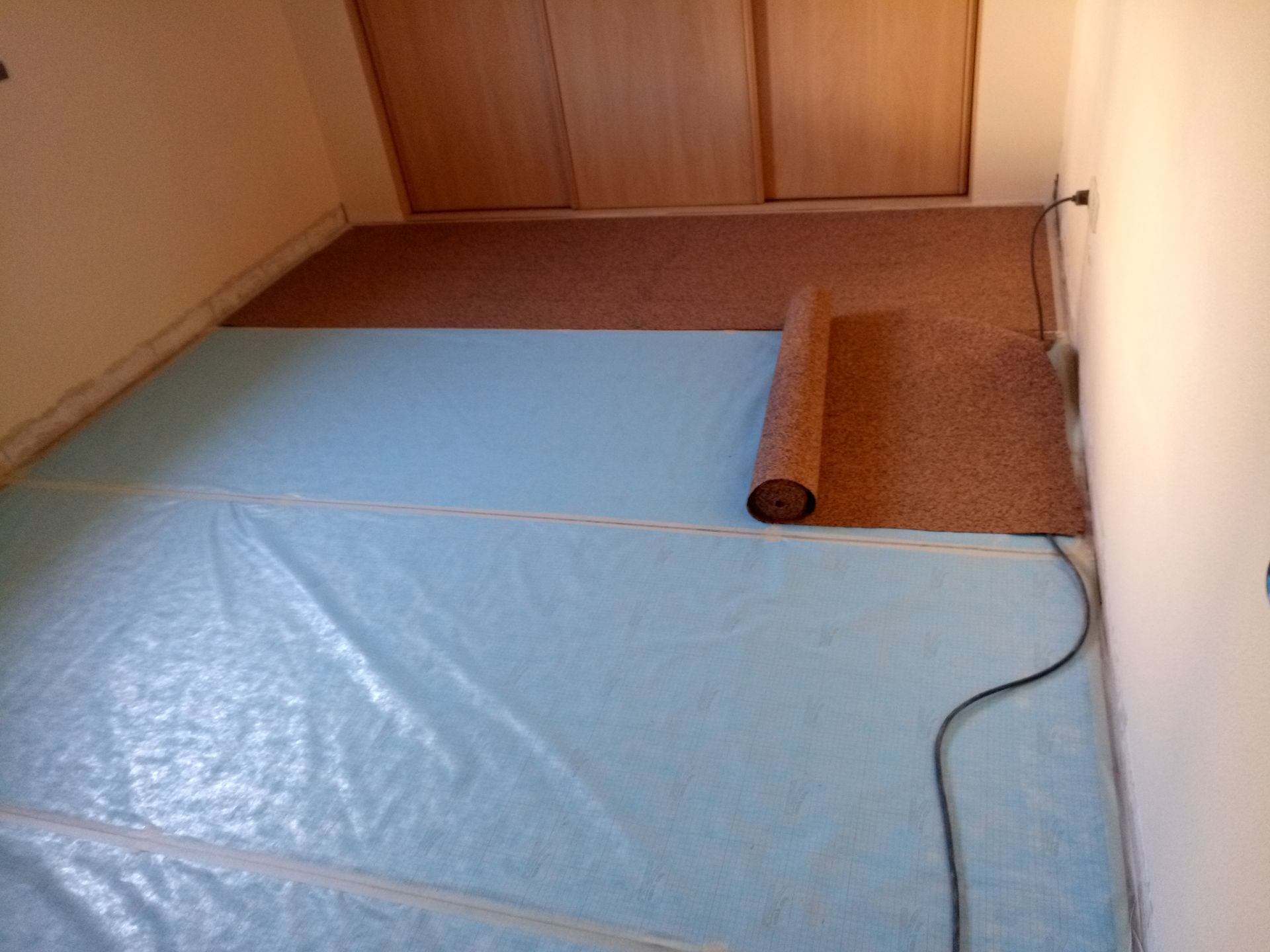 Quarto com base azul e carpete marrom estendido; preparação para instalação do piso.