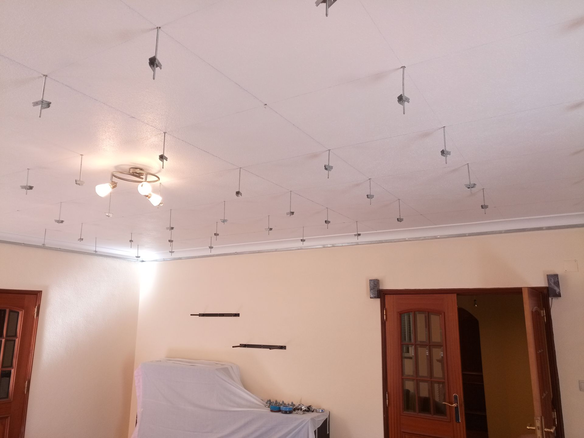 Teto do cômodo interno com fios de sustentação metálicos e moldura decorativa.