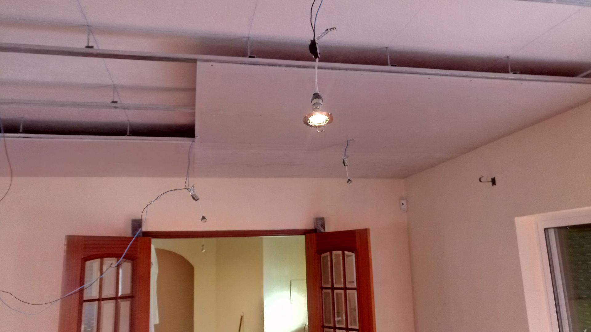 Construção do teto: instalação de drywall com fiação aparente e iluminação embutida. Cômodo com porta e janela.