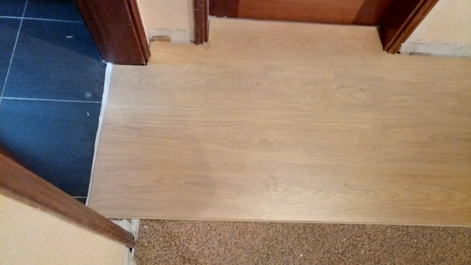 Piso de madeira e soleira da porta encontrando carpete e azulejo azul.