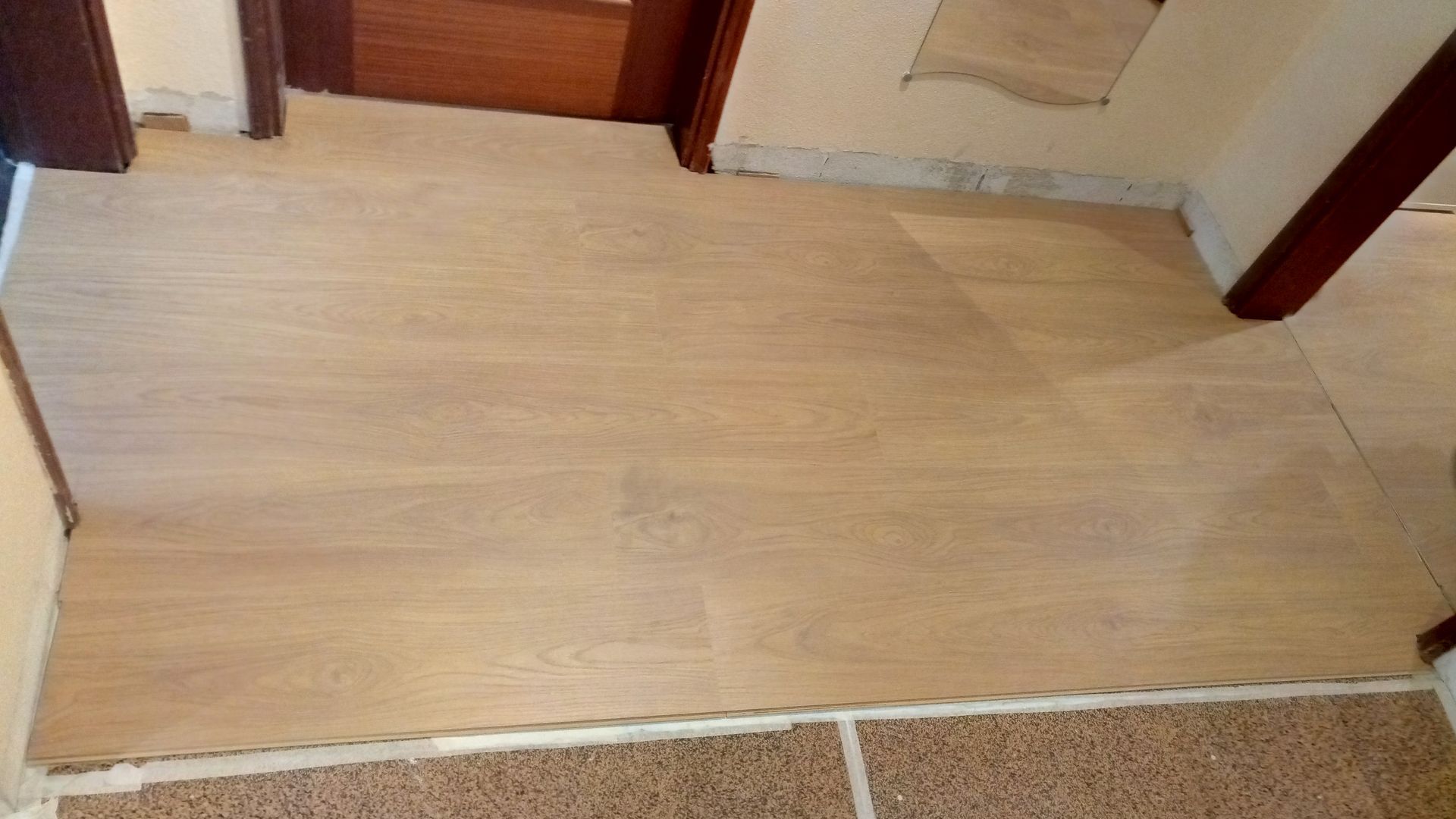 Piso de madeira clara instalado em um cômodo. As bordas possuem acabamento branco e um material semelhante à cortiça.