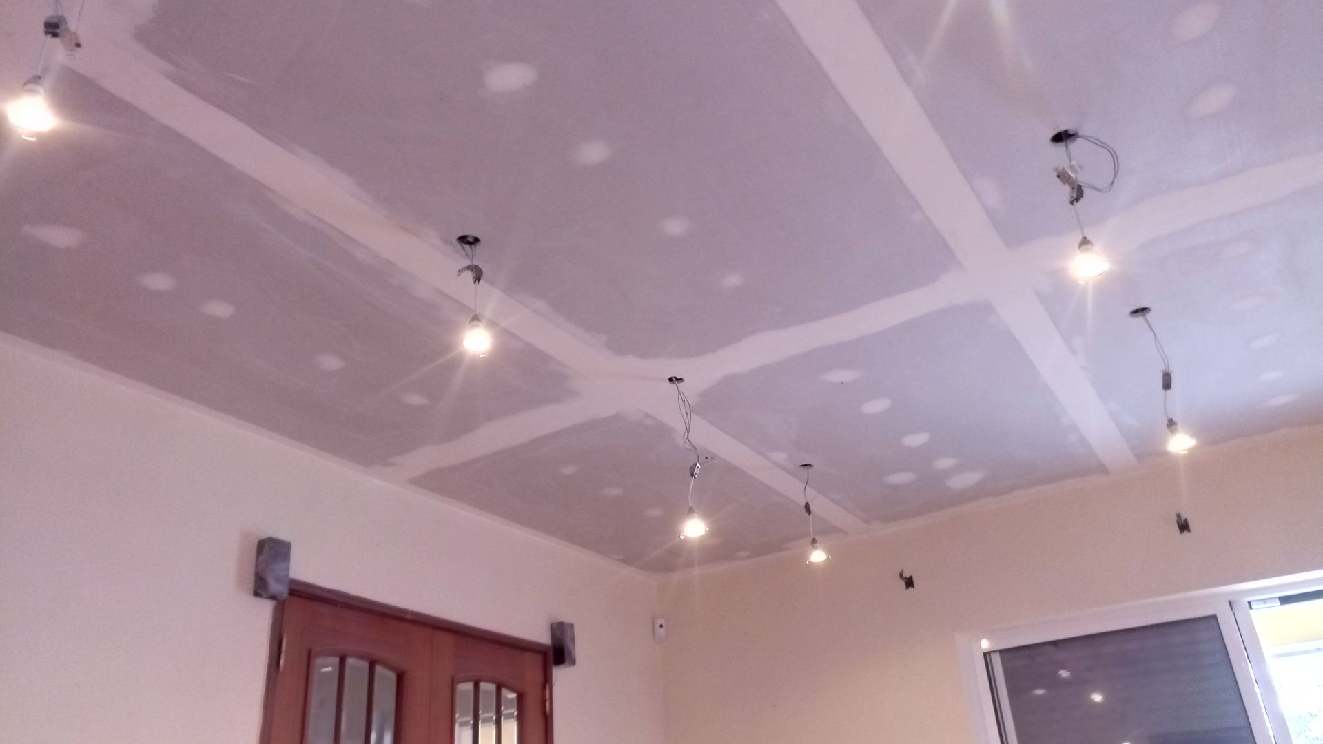 Teto com drywall instalado e luminárias suspensas em um cômodo com porta de correr.