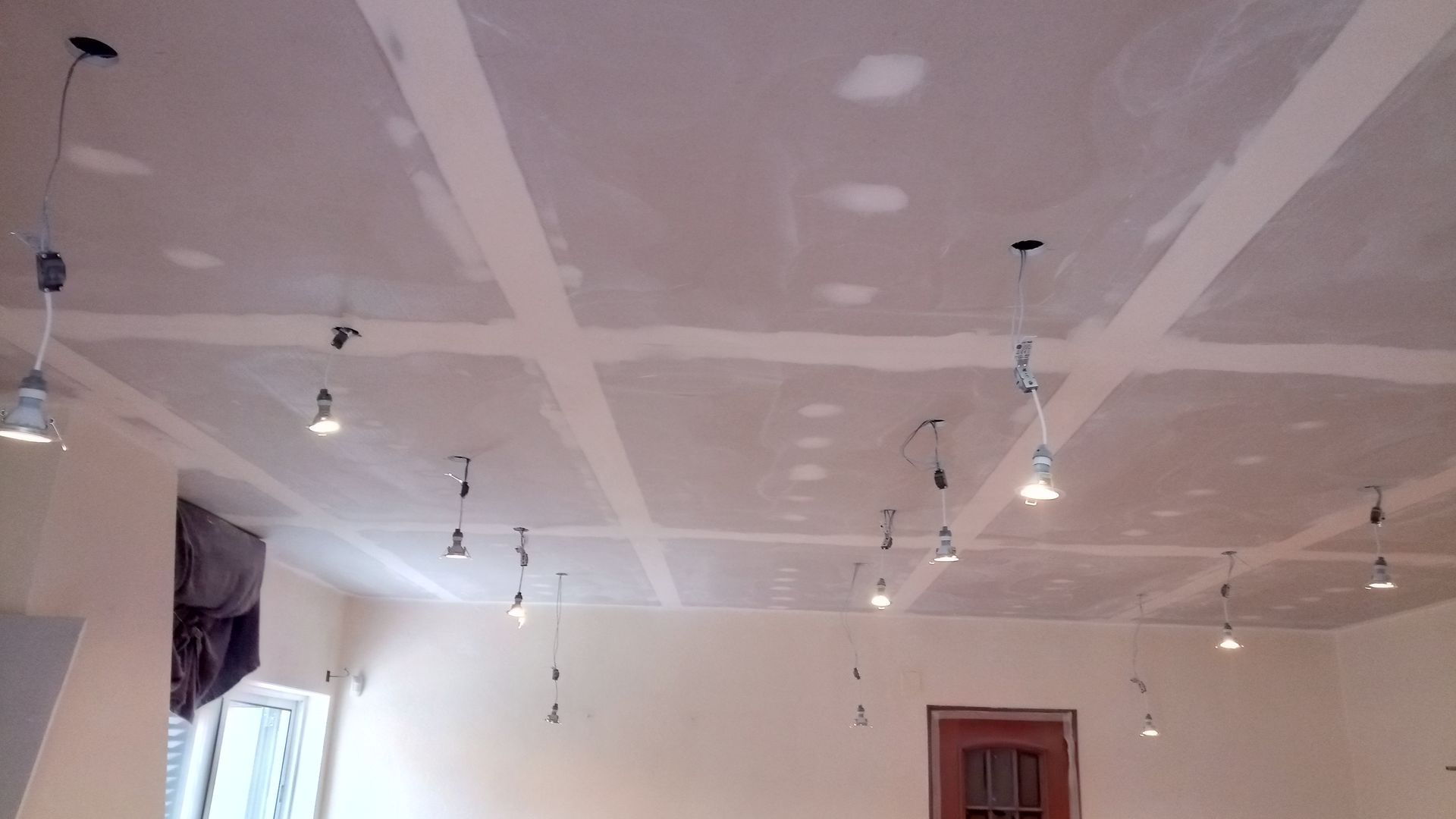Teto com drywall em construção, luminárias instaladas. Paredes e luminárias brancas.