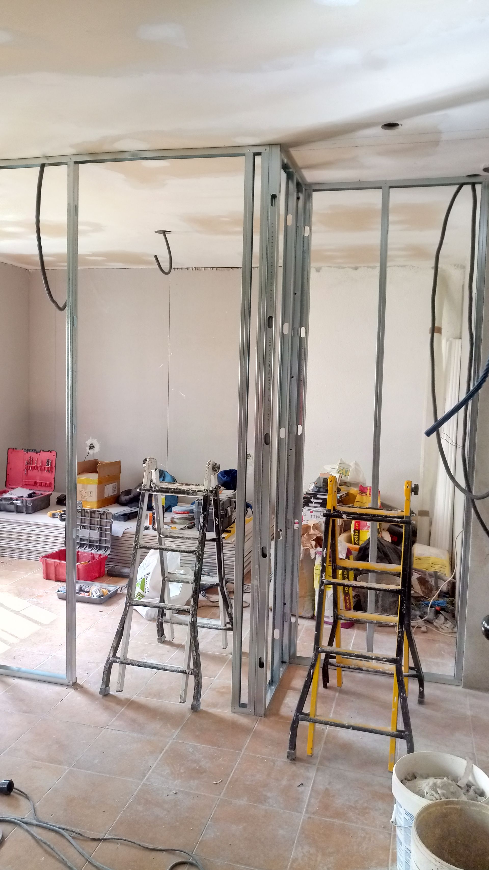 Estrutura metálica interna para parede, fiação e equipamentos visíveis durante a construção.