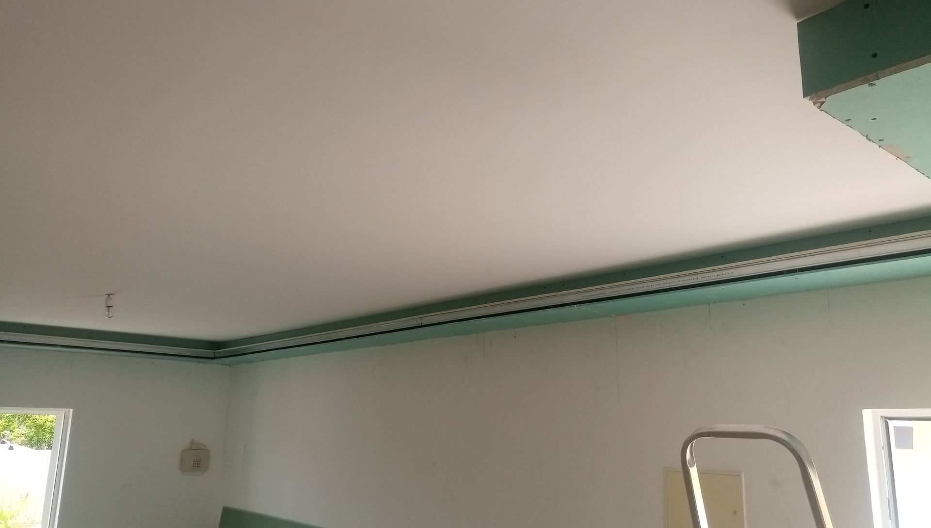 Teto e paredes brancas, detalhes em verde e um vislumbre de uma janela.