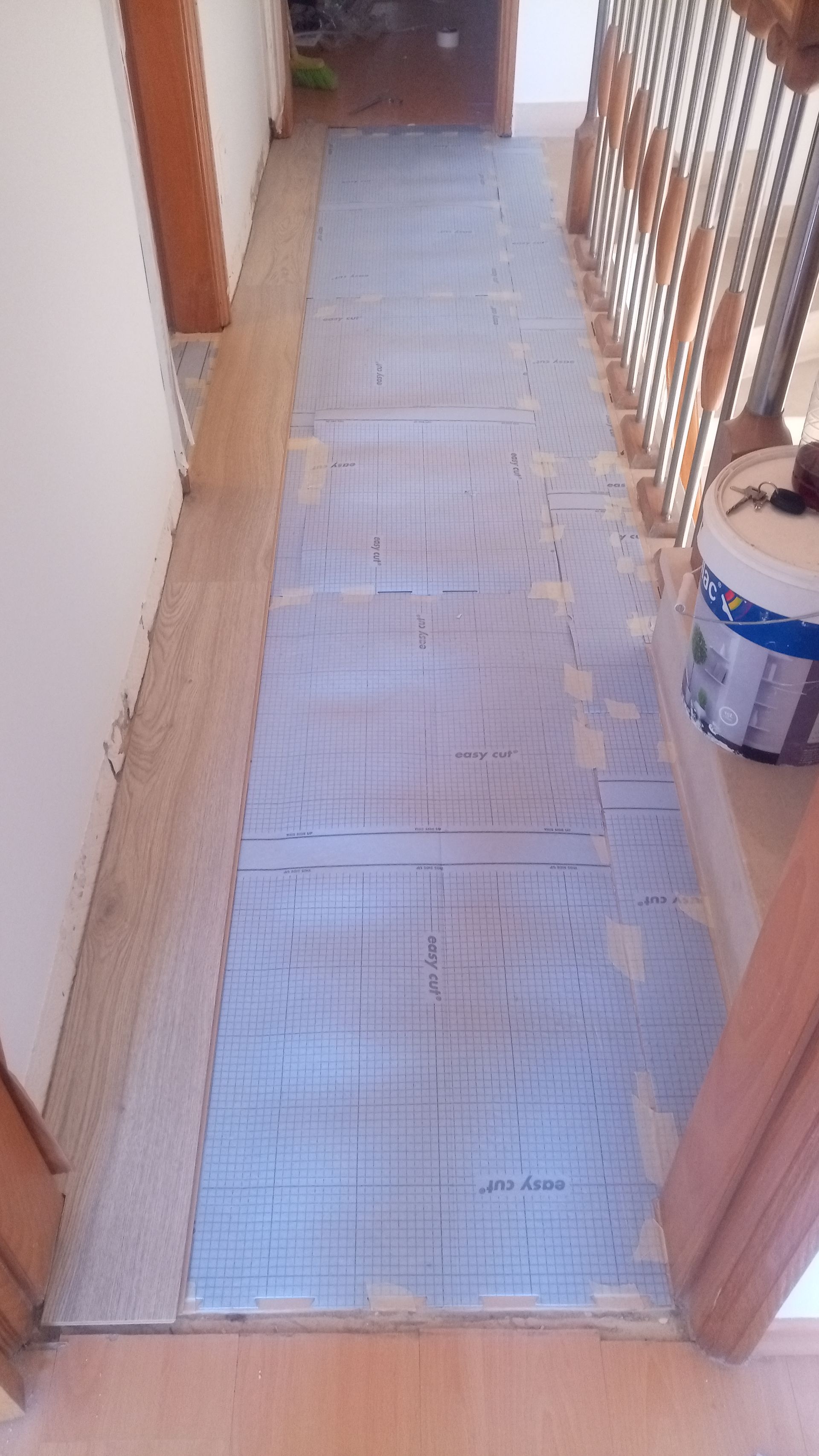 Corredor com base azul pronta para receber o piso; acabamentos e paredes em madeira clara.