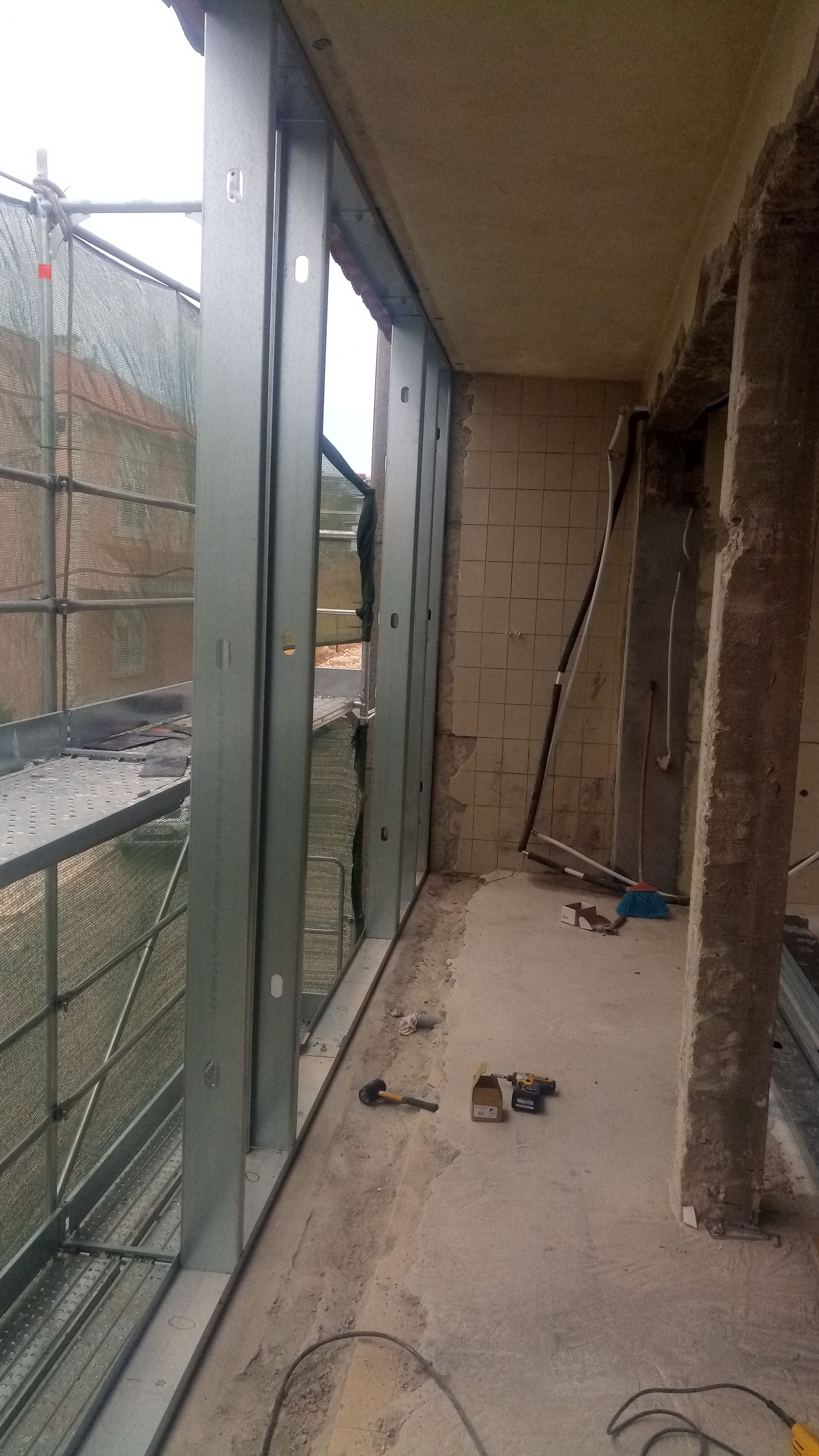 Caixilho metálico de janela instalado em um edifício durante a construção. Andaimes visíveis do lado de fora.