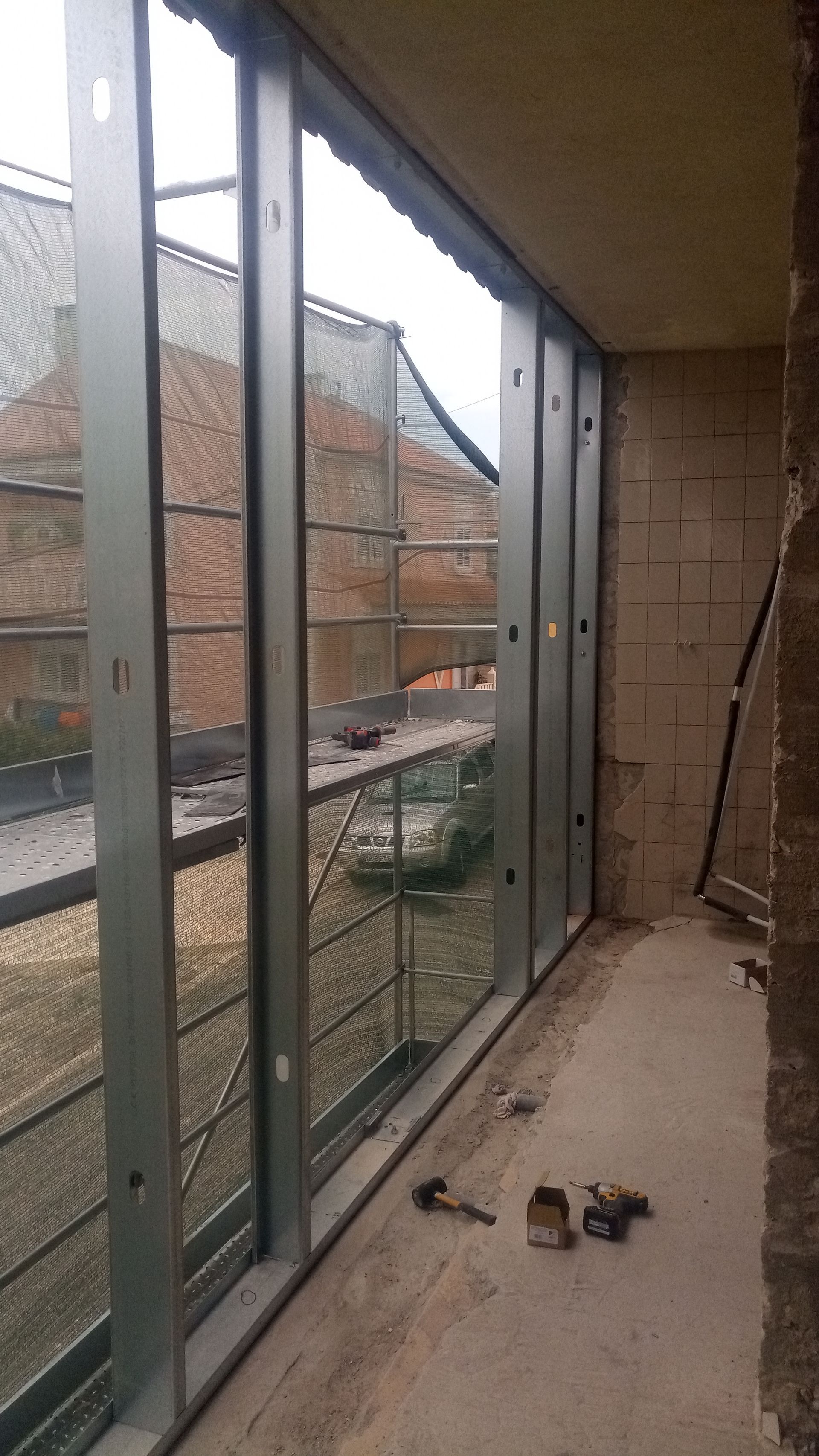 Estrutura metálica instalada para janelas e varanda, com vista para o exterior.