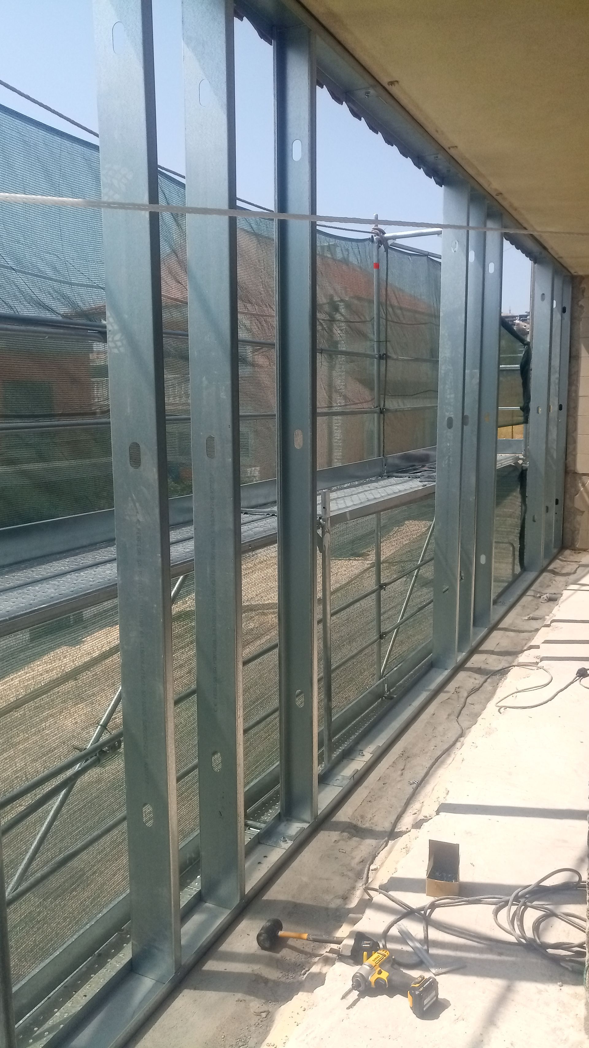 Estrutura metálica para a parede externa de um edifício. Construção inacabada com suportes visíveis e interior exposto.