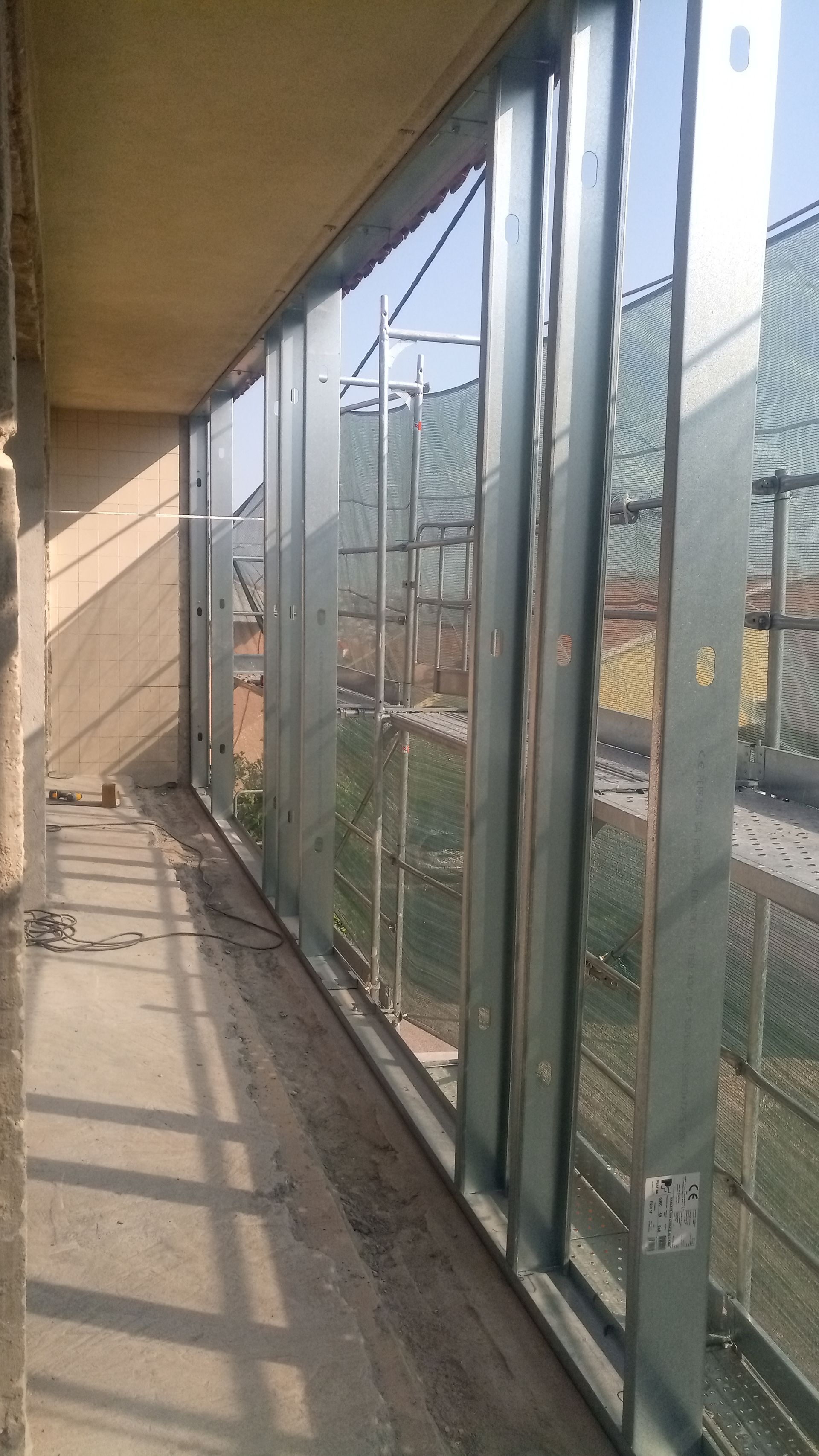 Estrutura metálica para uma parede de vidro em uma varanda, com entrada abundante de luz solar.