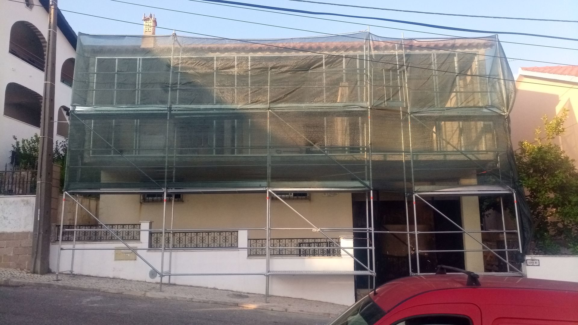 Prédio em reforma, andaimes cobertos com tela verde.