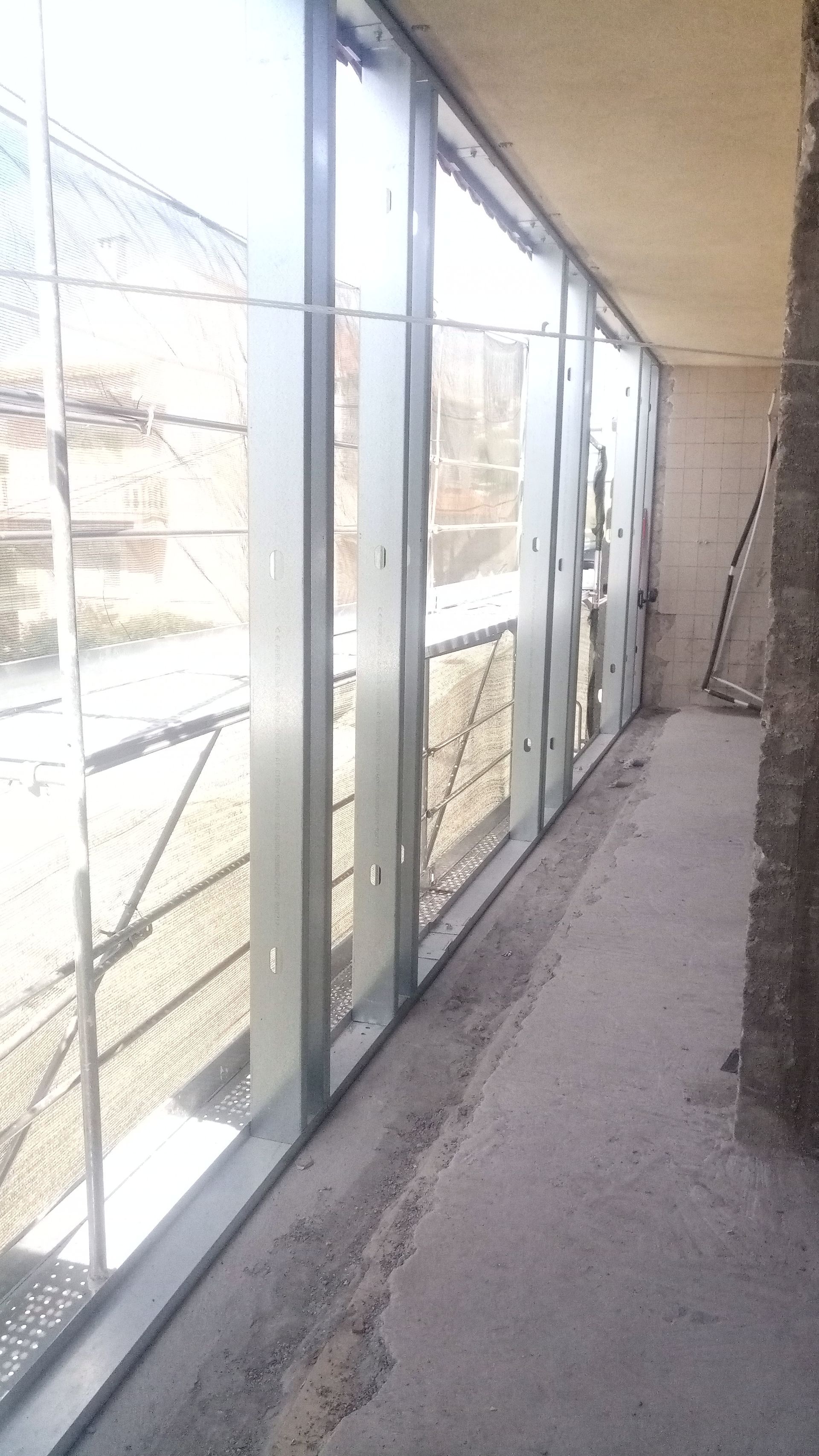 Interior de um canteiro de obras com uma longa fileira de caixilhos de janelas instalados.