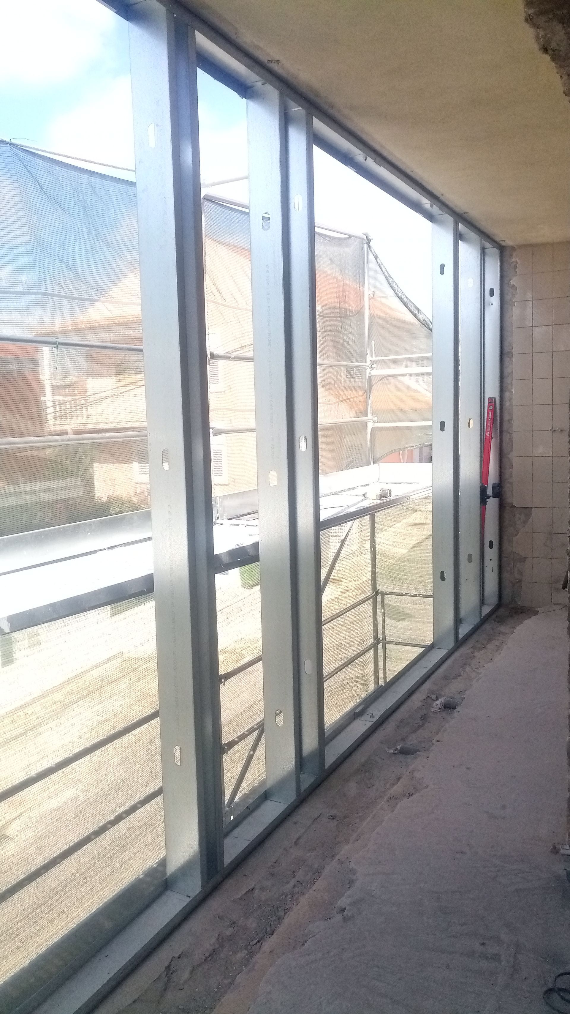 Painéis de vidro instalados em um edifício durante a construção, exibindo uma vista para o exterior.