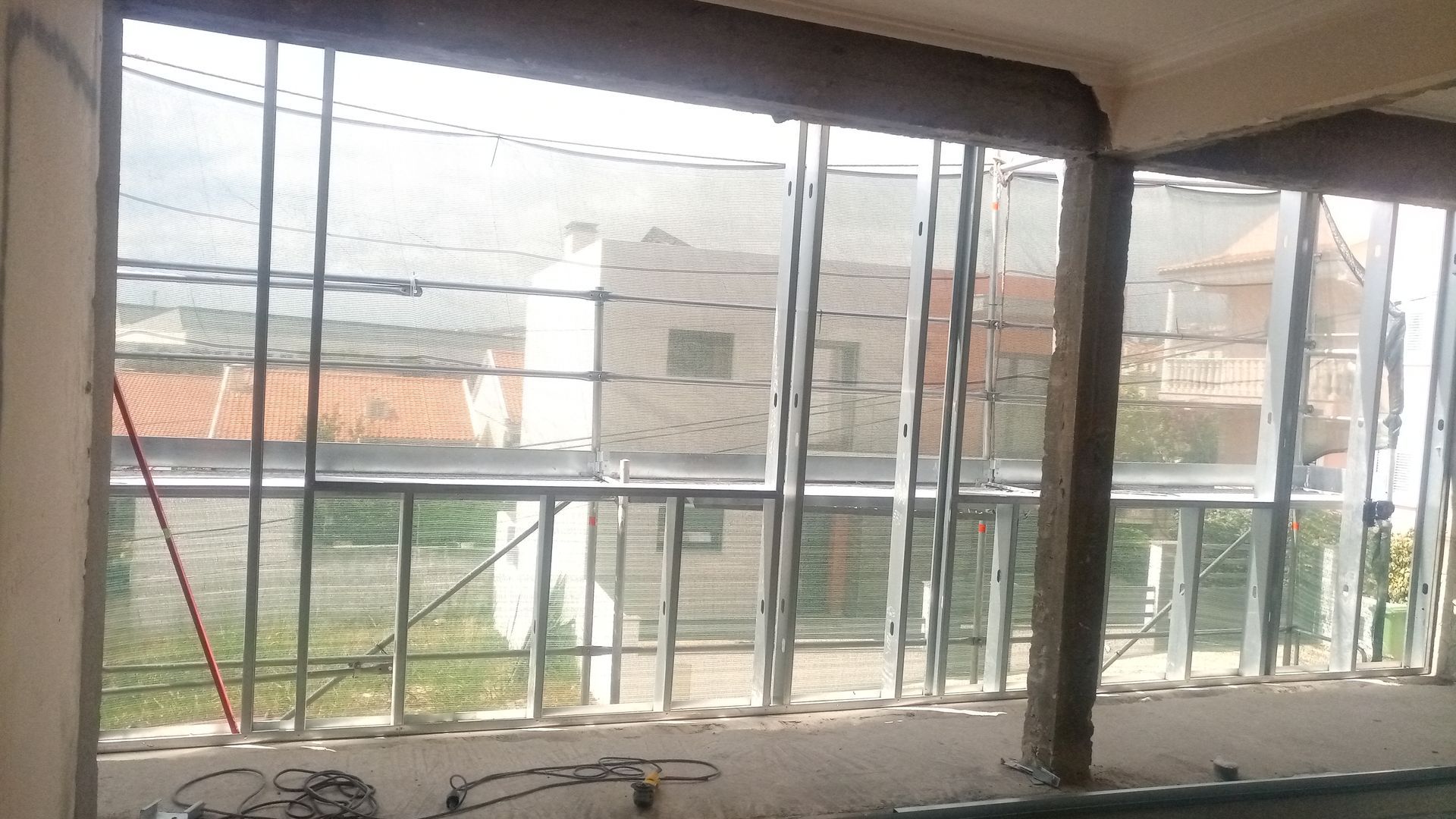 Janela ampla com vários painéis de vidro com vista para os prédios da vizinhança.