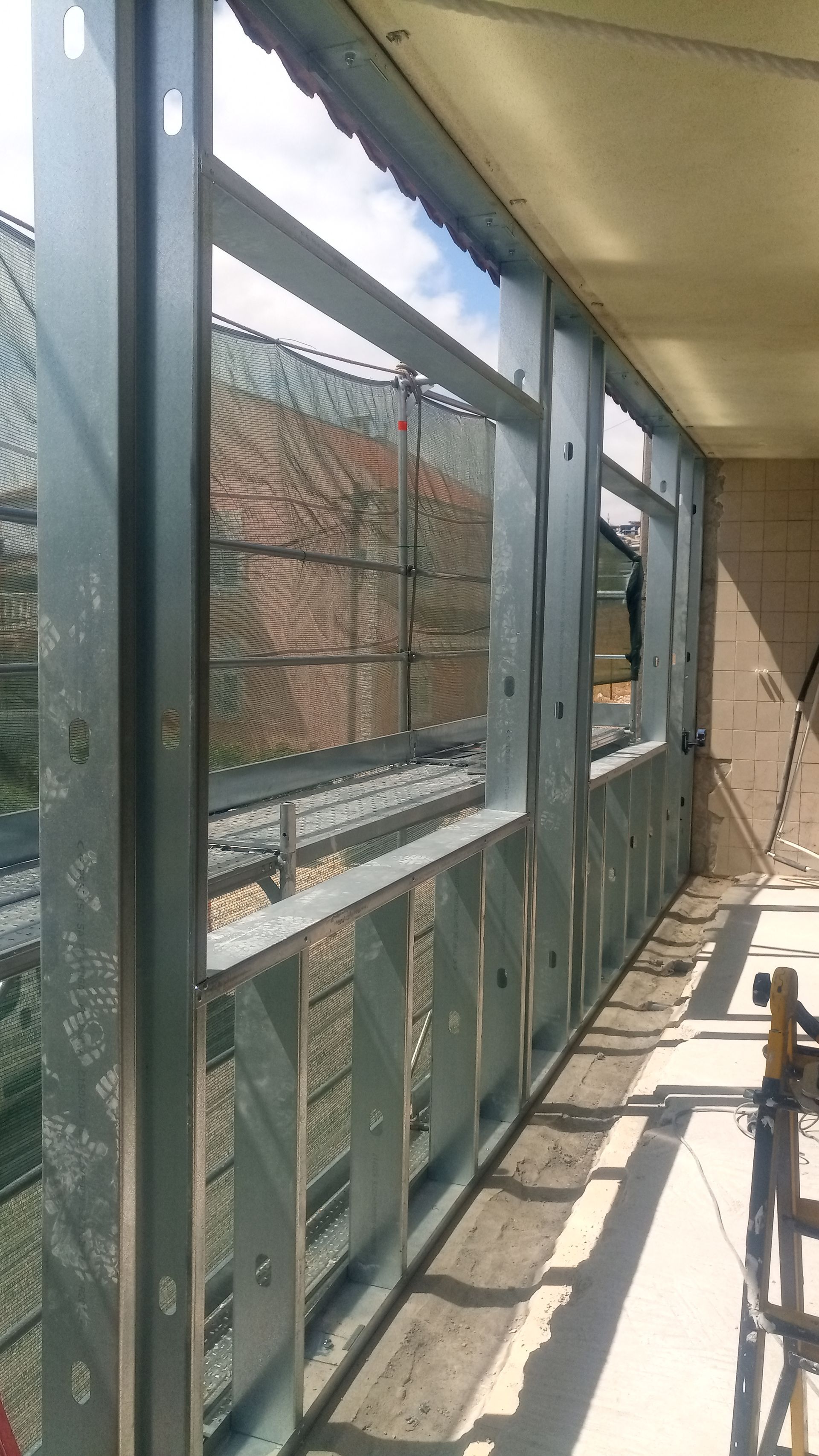 Estrutura metálica para uma janela ou parede em construção; a luz natural entra pelas aberturas.