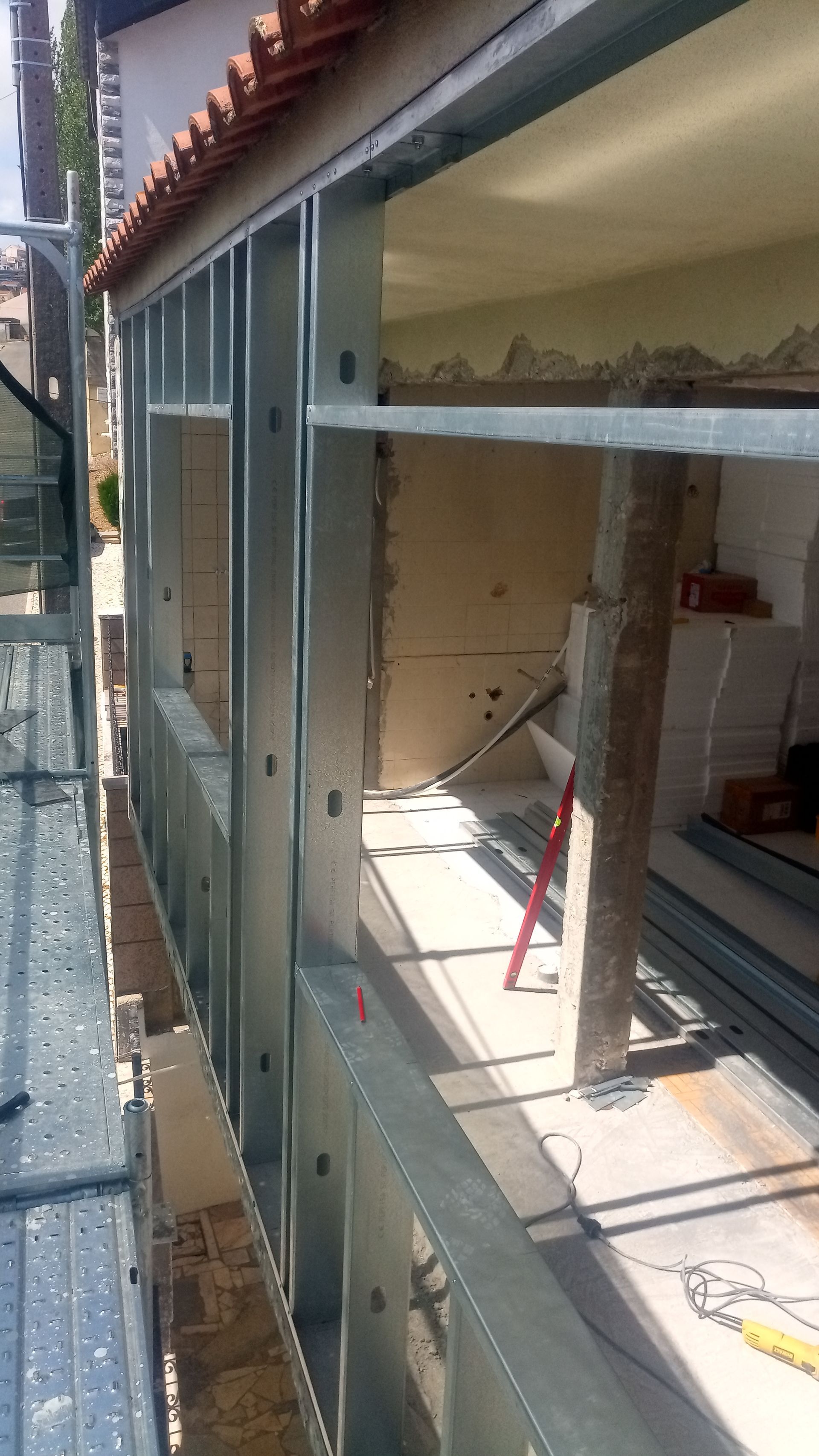 Estrutura metálica de uma varanda externa em construção, vista de uma plataforma de andaime.