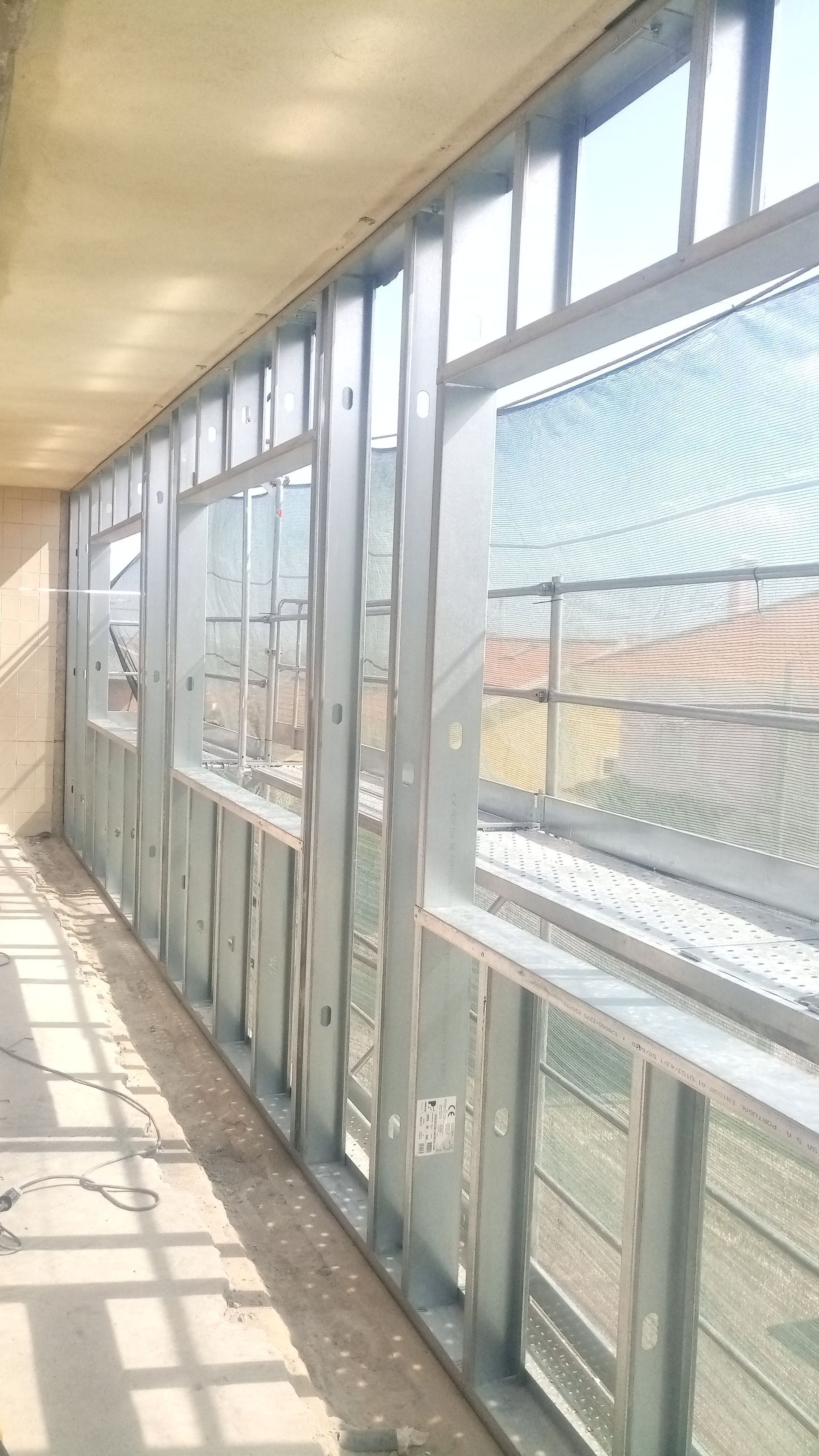 Estrutura metálica para parede com aberturas retangulares para janelas, interior de obra.