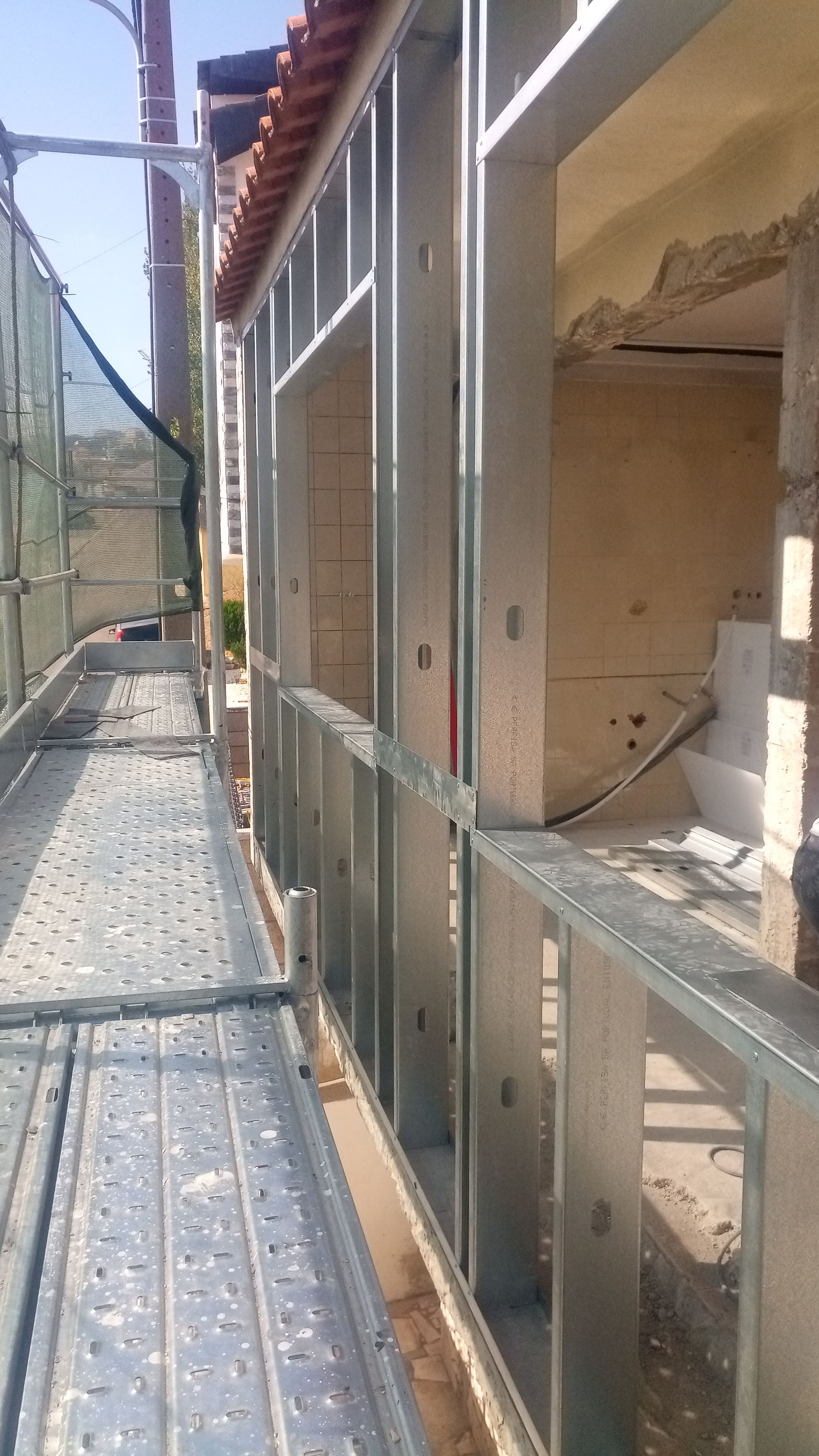 Estrutura metálica instalada na parte externa de um prédio em construção, com andaimes ao lado.