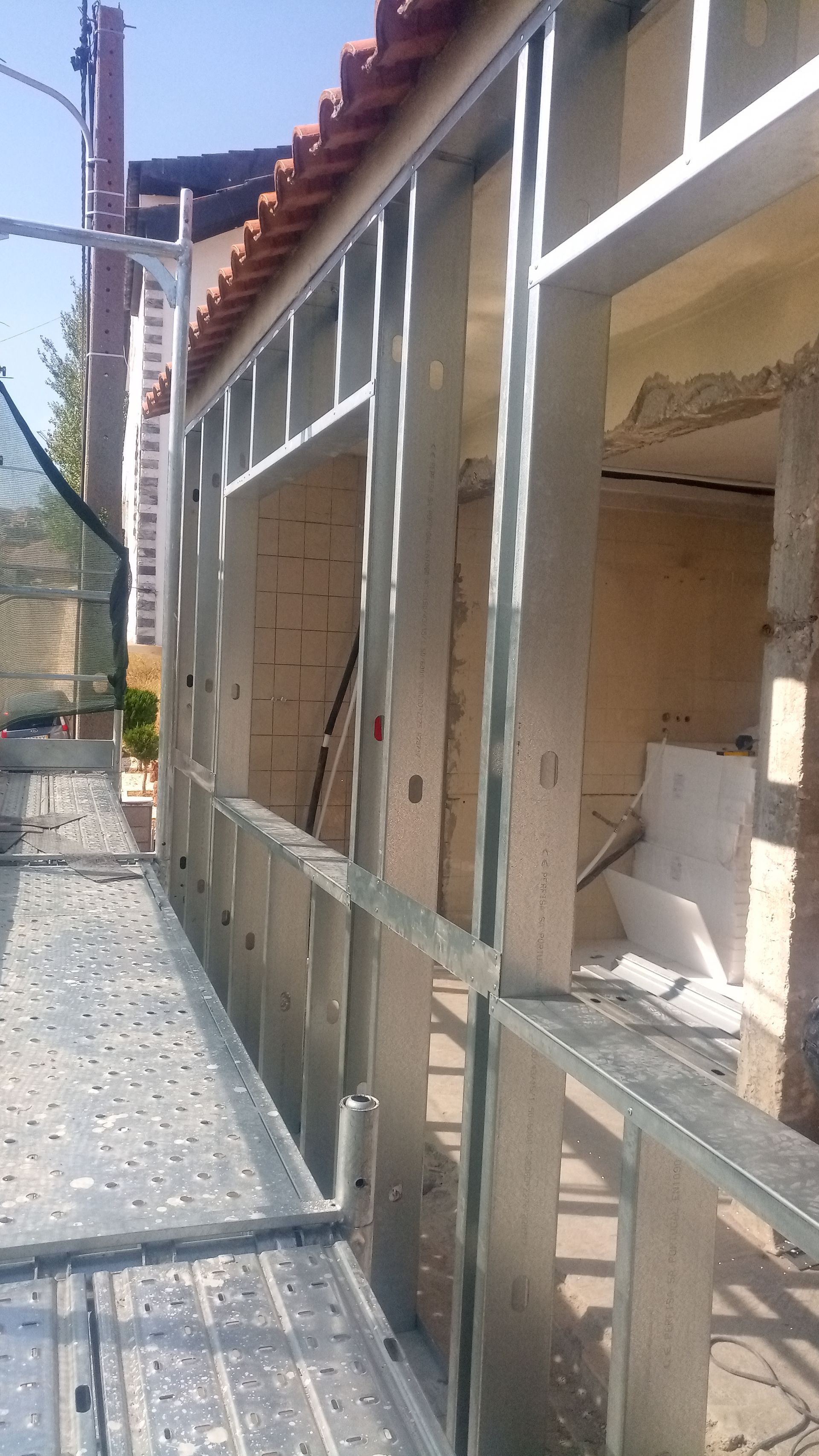 Estrutura metálica na parte externa de um edifício, com andaimes e paredes de tijolos visíveis.