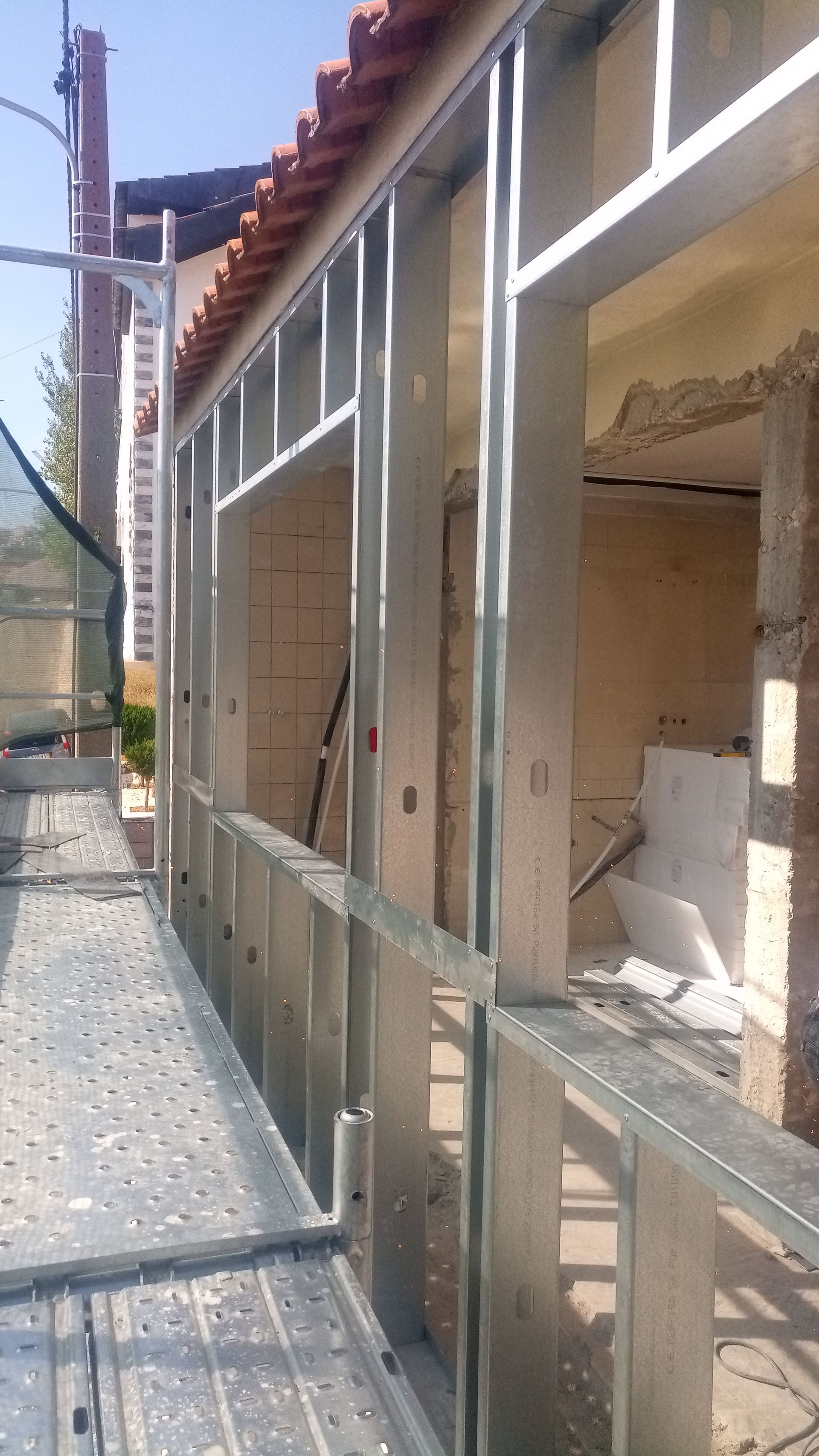 Estrutura metálica para o exterior de um edifício em construção, com andaimes ao lado.