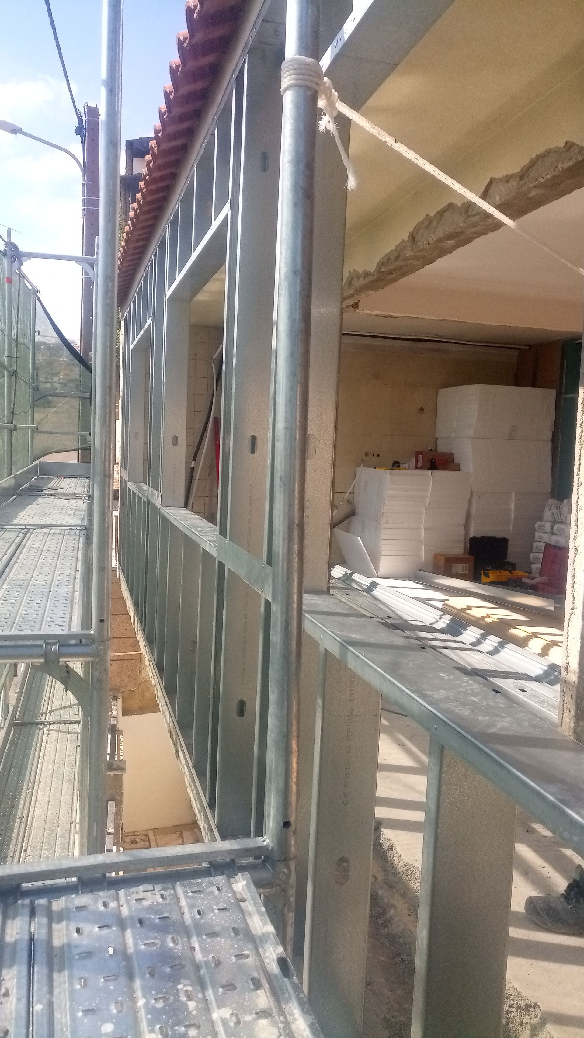 Canteiro de obras com andaimes metálicos, estrutura e interior exposto.