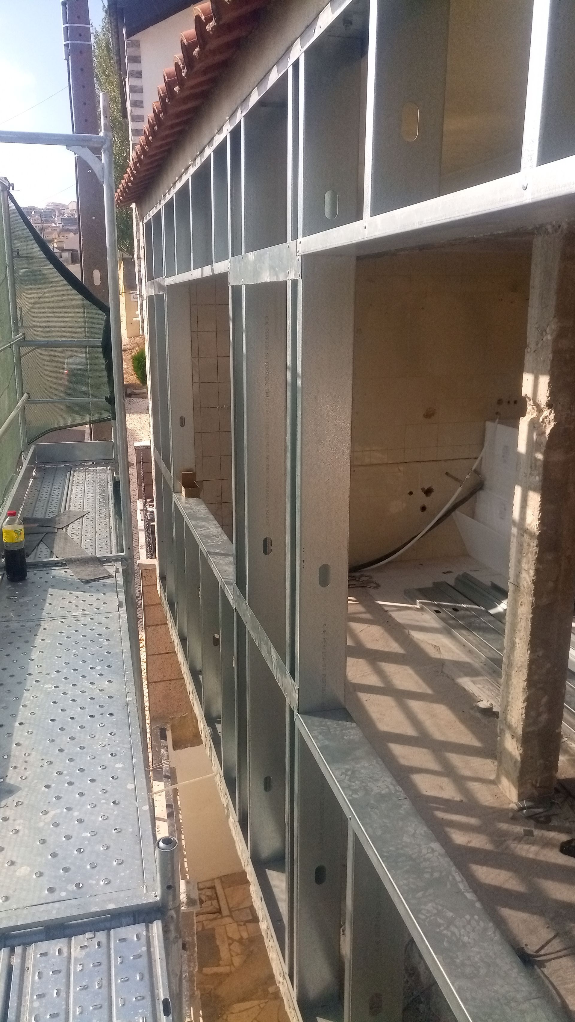 Canteiro de obras: Estrutura metálica de uma varanda. Andaimes visíveis.