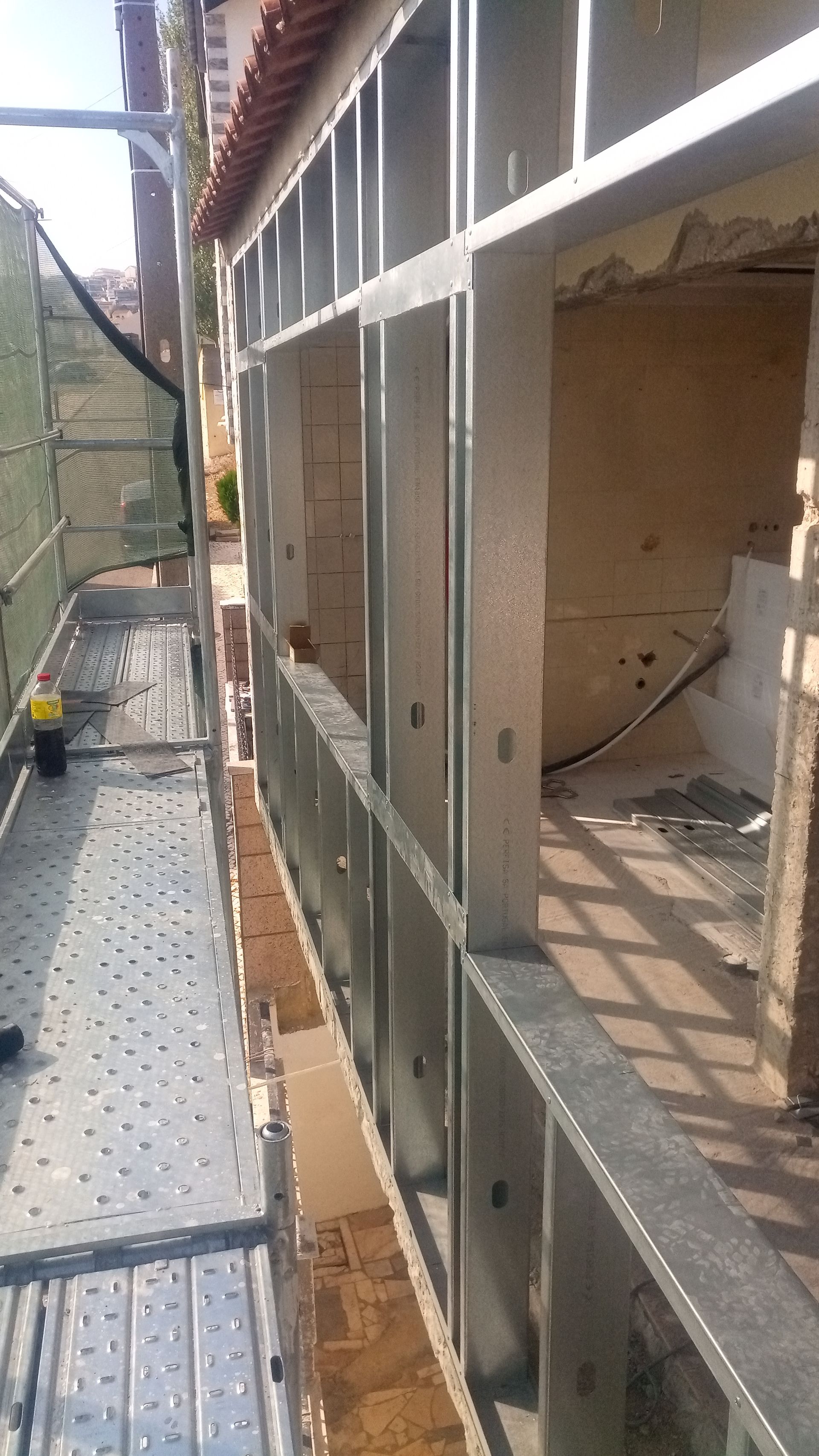 Estrutura metálica para o exterior de um edifício, com andaimes e parte da fachada.