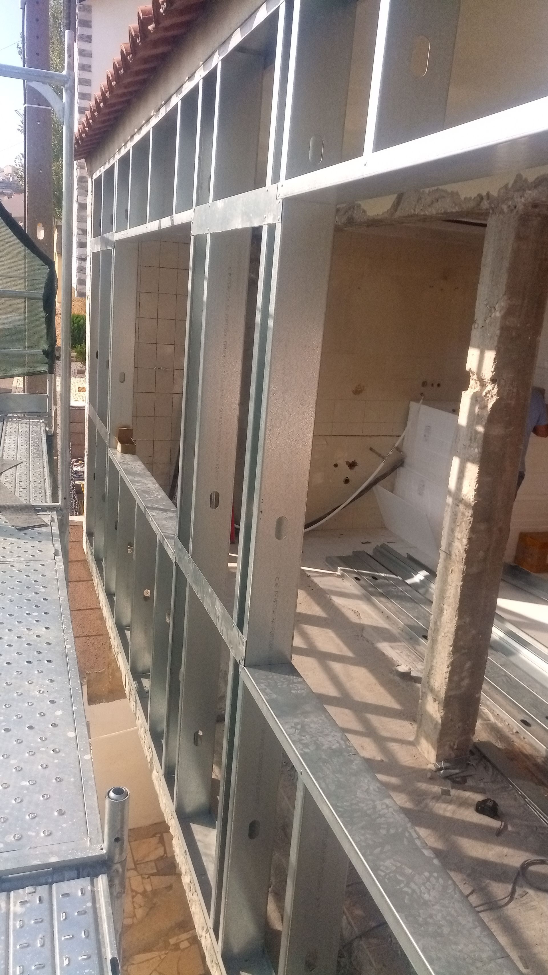 Estrutura metálica da parede externa de um edifício em construção. Andaimes visíveis no lado esquerdo.