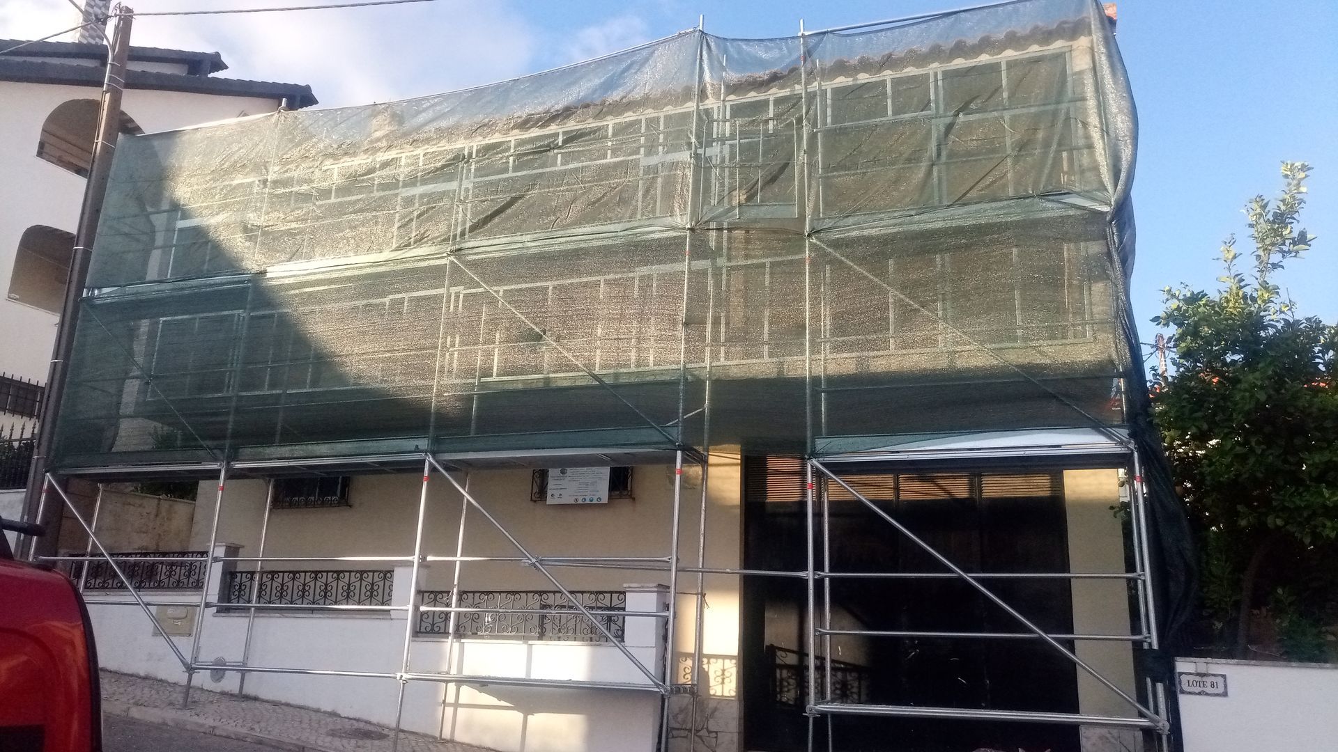 Prédio em construção, coberto por andaimes e tela verde.