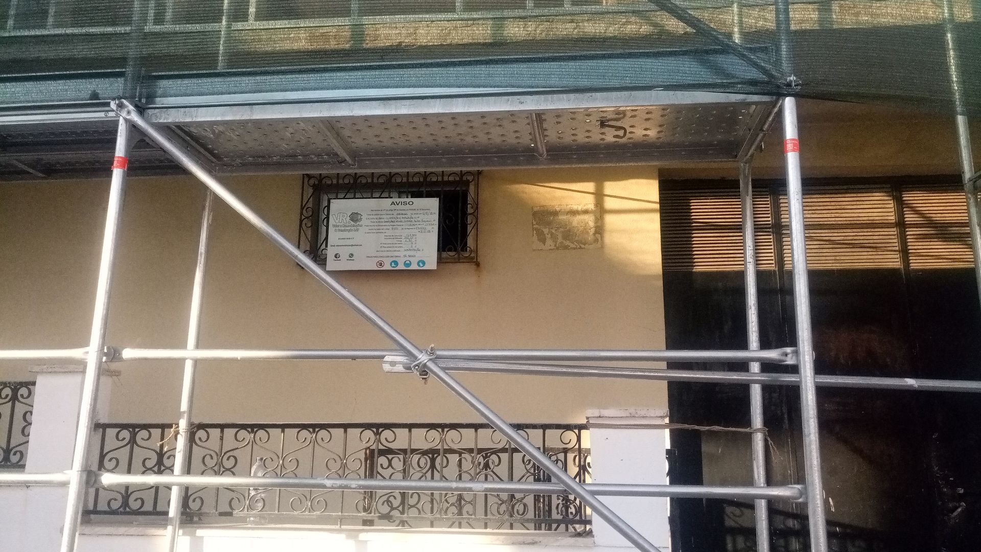 Andaimes em frente a um prédio com uma janela e uma placa.